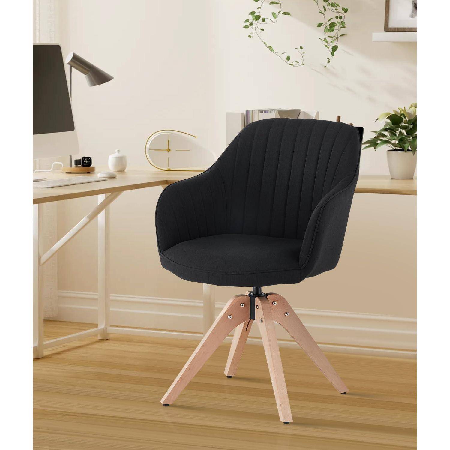 Schwarzer gepolsterter Drehstuhl mit hellen Holzbeinen in einem hellen Homeoffice neben einem Schreibtisch und einer Lampe.