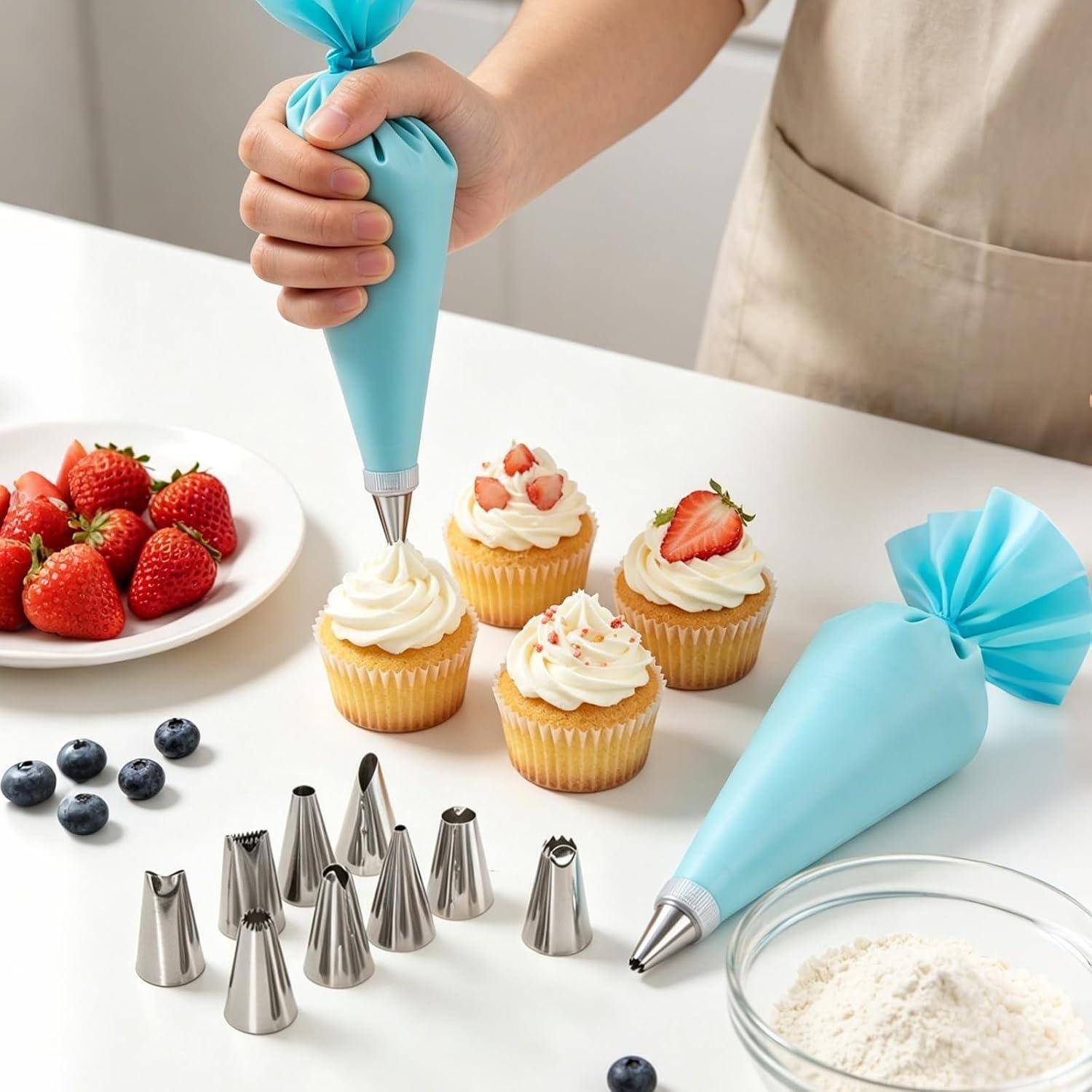 Eine Cupcake mit einer blauen Spritztüte von Hand verzieren; Cupcakes, Erdbeeren, Blaubeeren, Gebäckspitzen und Mehl auf einer Küchentheke.