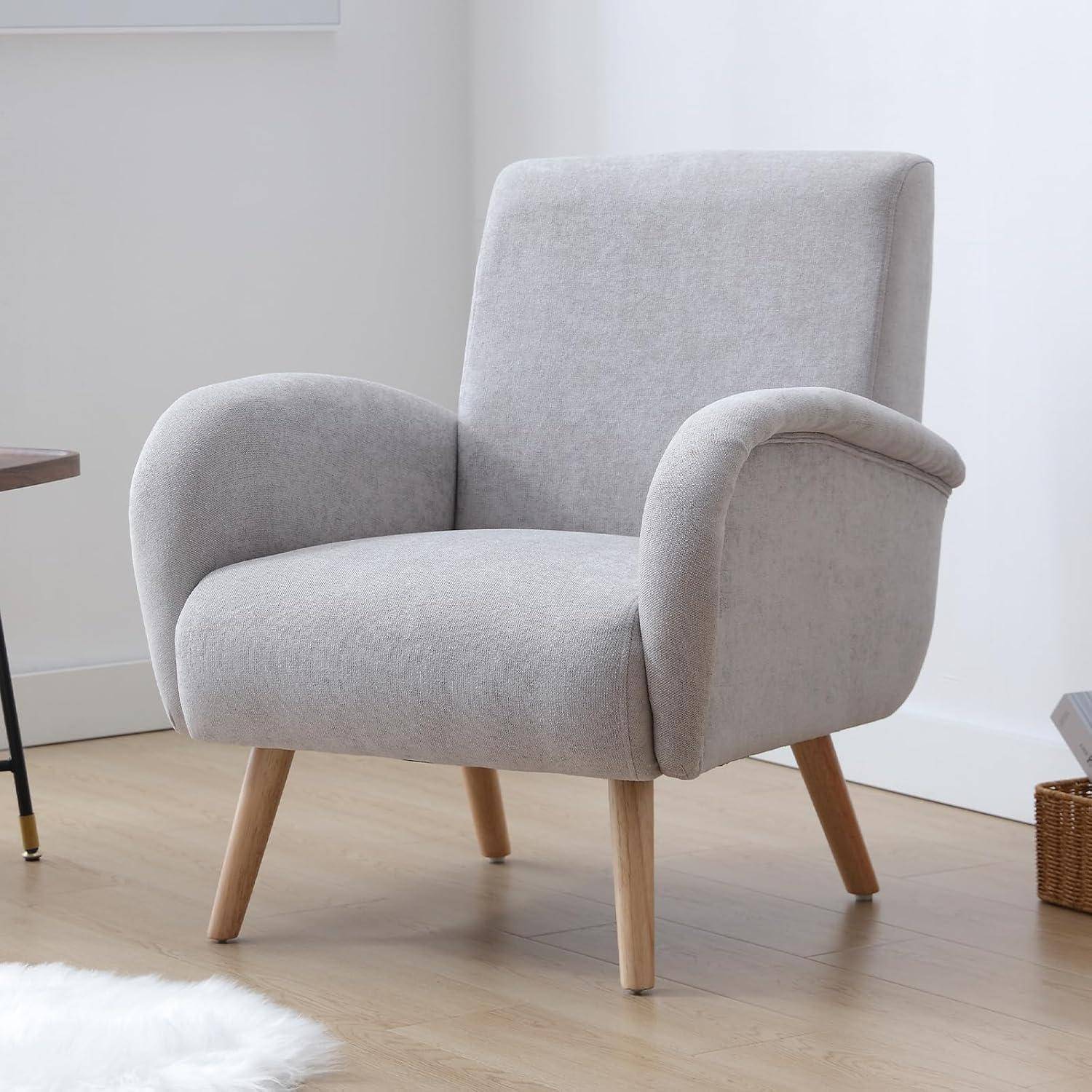 Hellgrauer, polsterter Sessel mit abgerundeten Armlehnen und Holzbeinen in einem minimalistischen Zimmer.