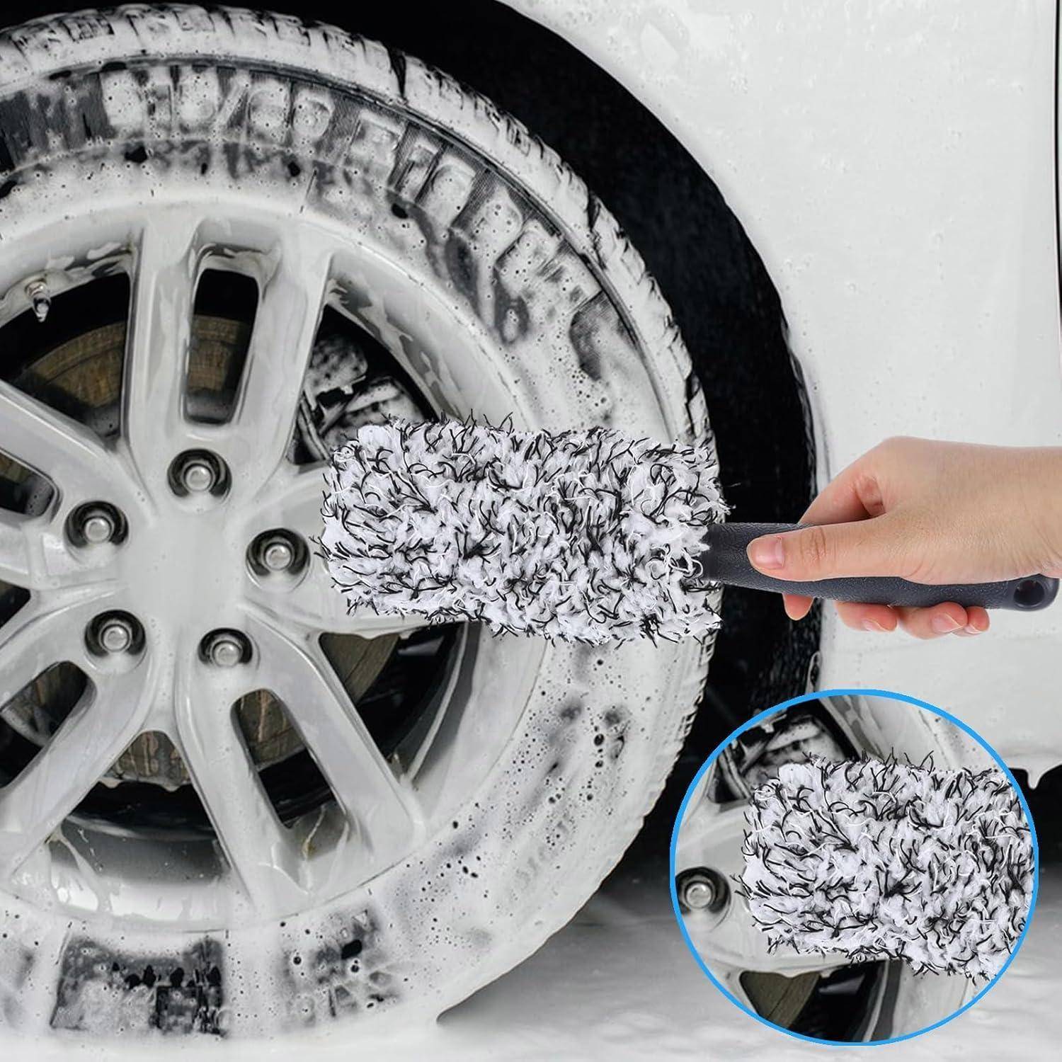 Eine Hand benutzt eine schaumige Bürste, um die Felge eines Autoreifens zu reinigen, mit einer vergrößerten Nahaufnahme, die das Bürsten-Detail zeigt.