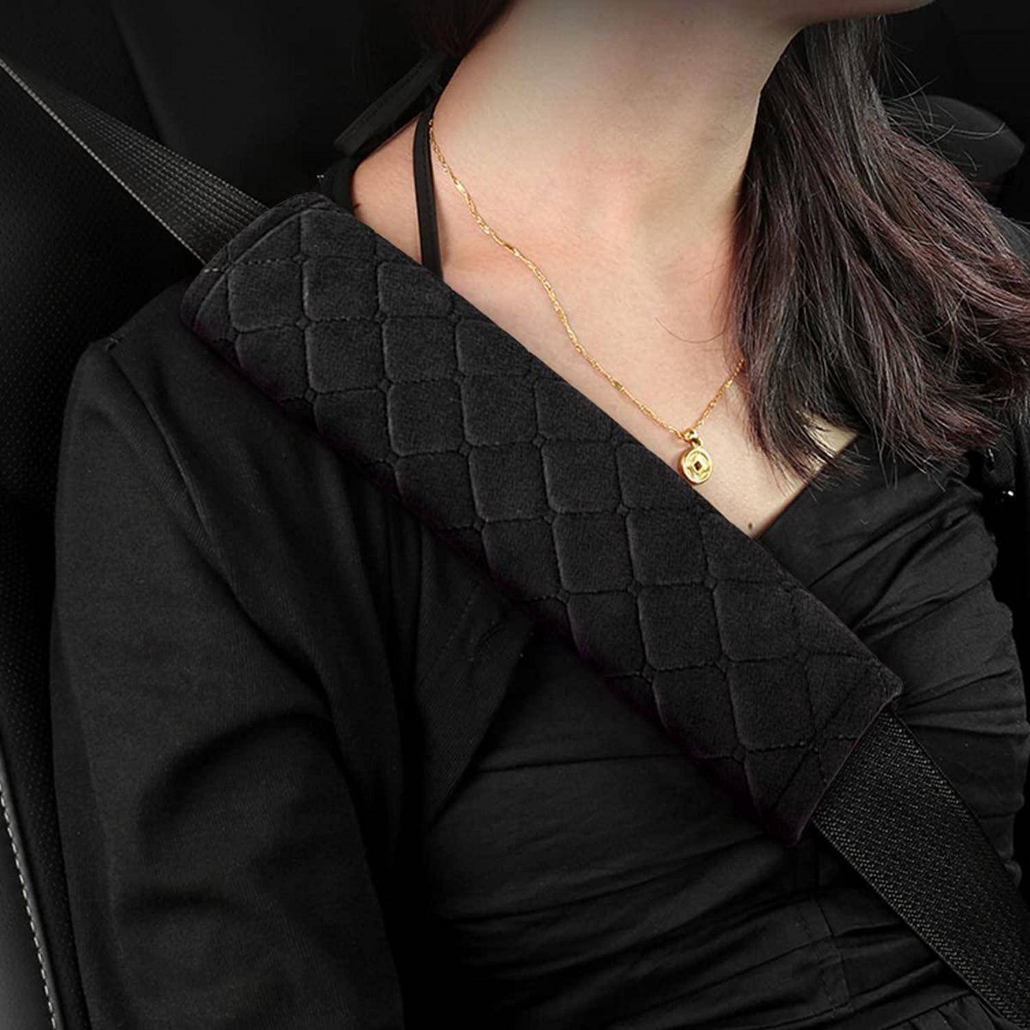 Nahaufnahme einer Frau, die ein schwarzes Wickeltop und eine goldene Anhängerkette trägt, mit einem schwarzen strukturierten Schultergurt über ihrer Brust.