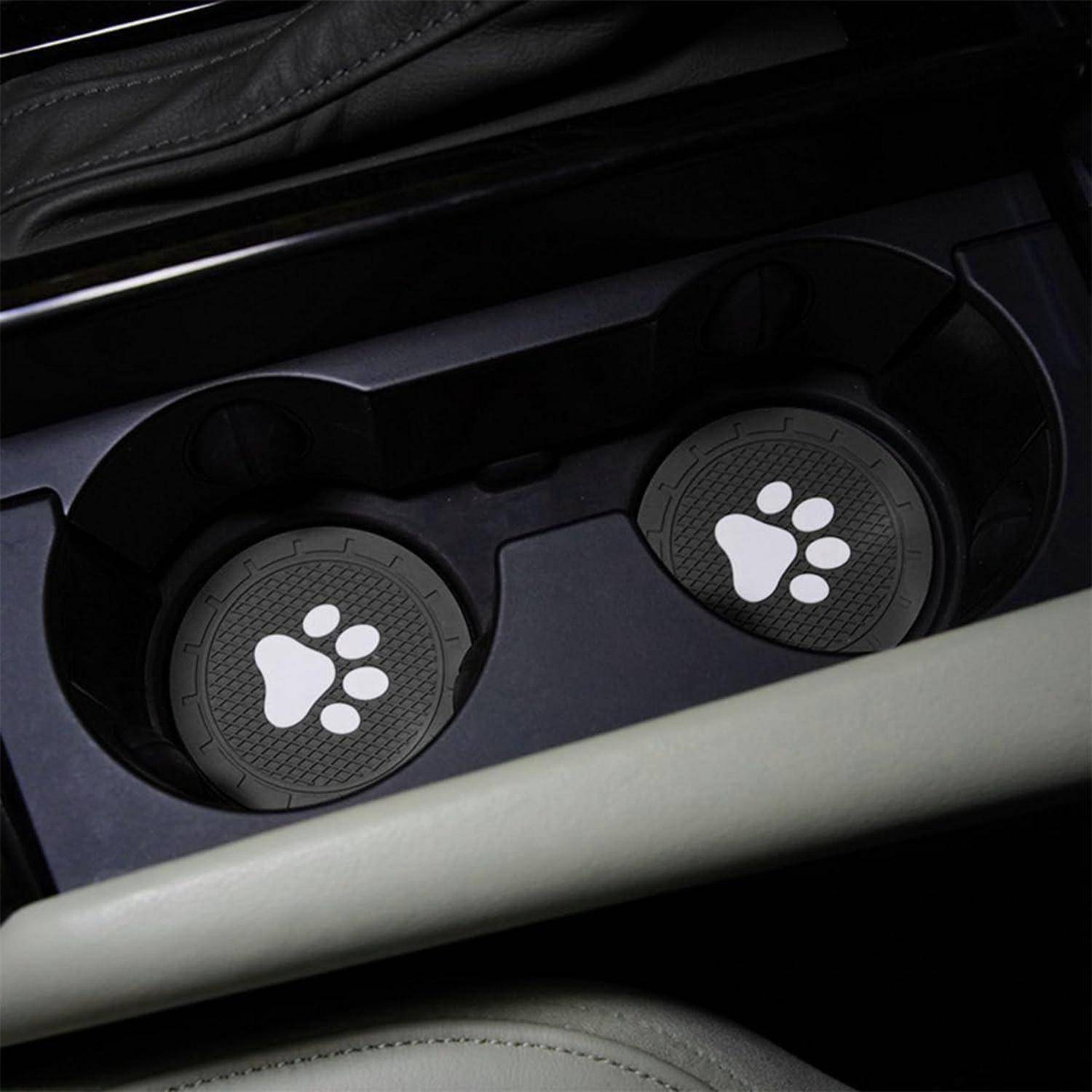 Zwei Getränkehalter in einer Auto-Mittelkonsole, jeder mit einem schwarzen Deckel mit einem weißen Pfotendruck-Symbol bedeckt.