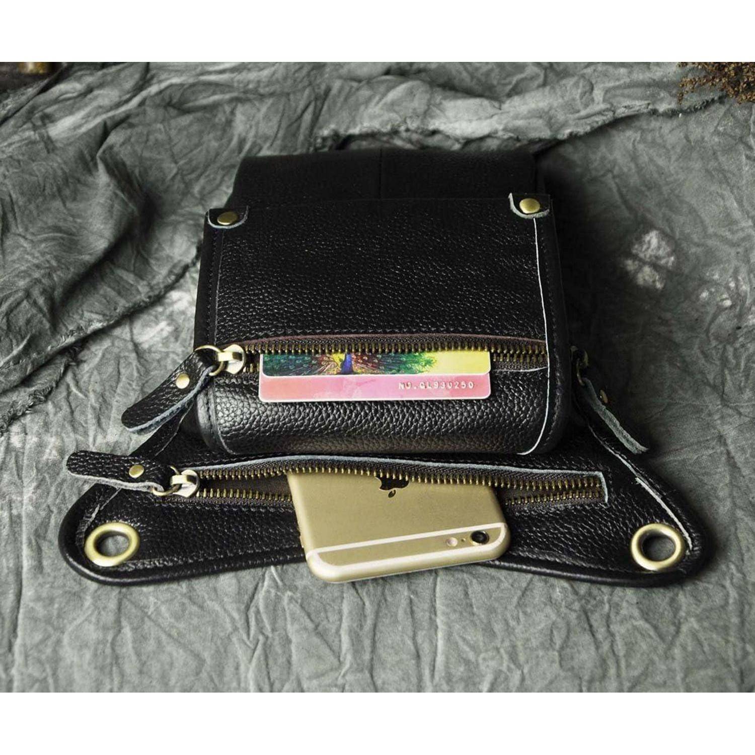 Schwarze Lederbörse mit Reißverschluss und einem Telefon in der vorderen Tasche, geöffnet auf grauem Stoffhintergrund dargestellt.