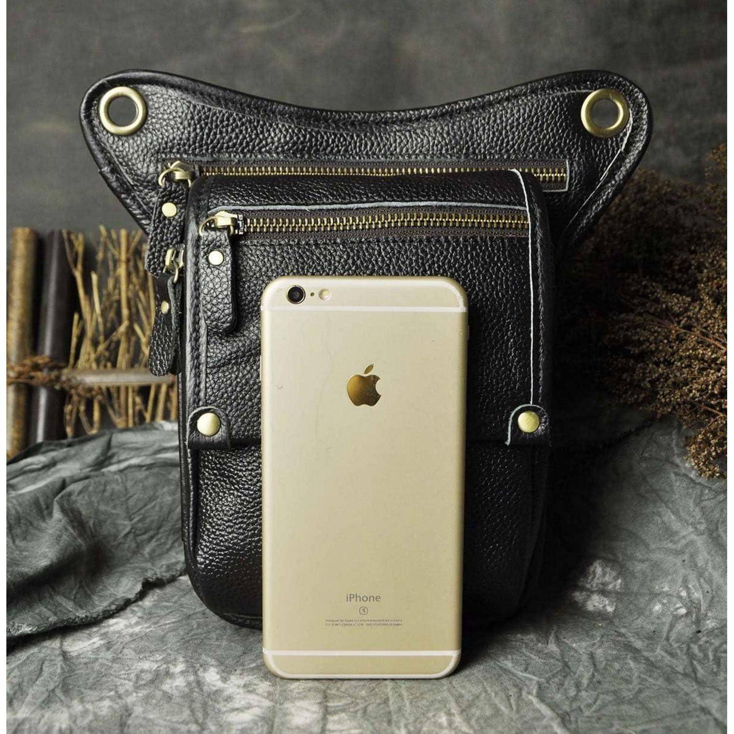 Ein goldenes iPhone lehnt an einem schwarzen Lederrucksack mit goldenen Reißverschlüssen und Ringen auf einer grauen strukturierten Oberfläche.