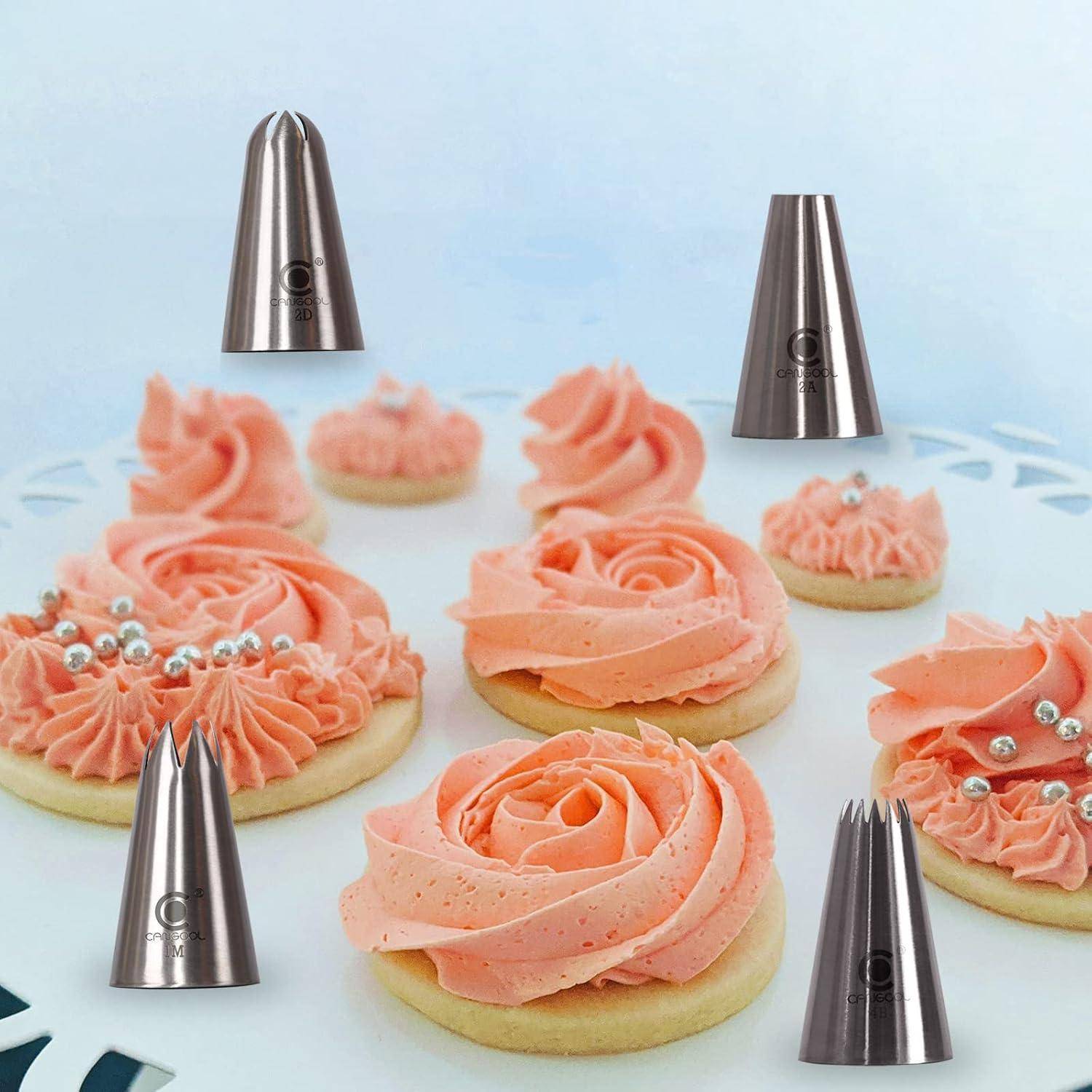 Verschiedene blumenförmige Zuckerkekse mit rosa Zuckerguss-Rosen, umgeben von Dekorationsspritzaufsätzen auf einem weißen Tablett.