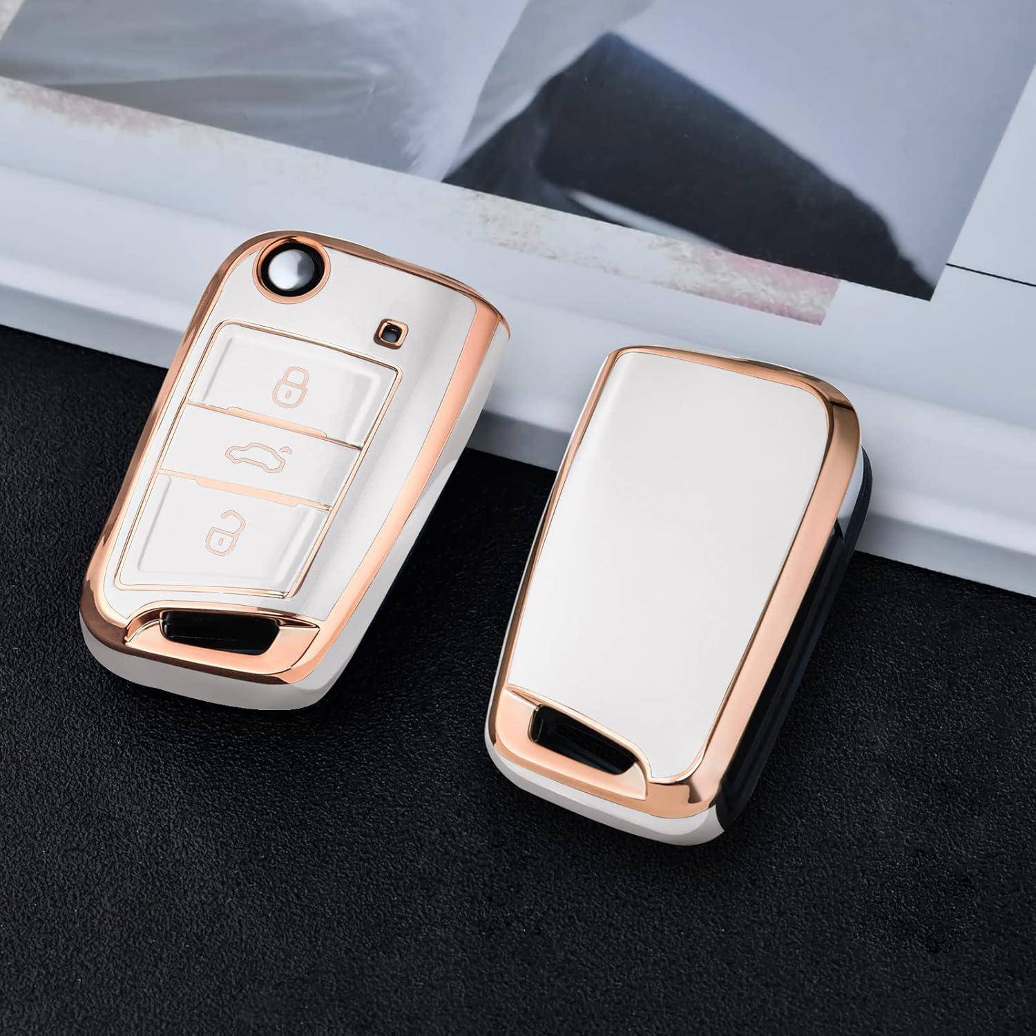 Zwei weiß-roségold Autoschlüsselbänder auf einer dunklen Oberfläche, eines zeigt Sperr- und Entsperrtasten sowie ein Kofferbaumsymbol, das andere Rückseite nach oben.