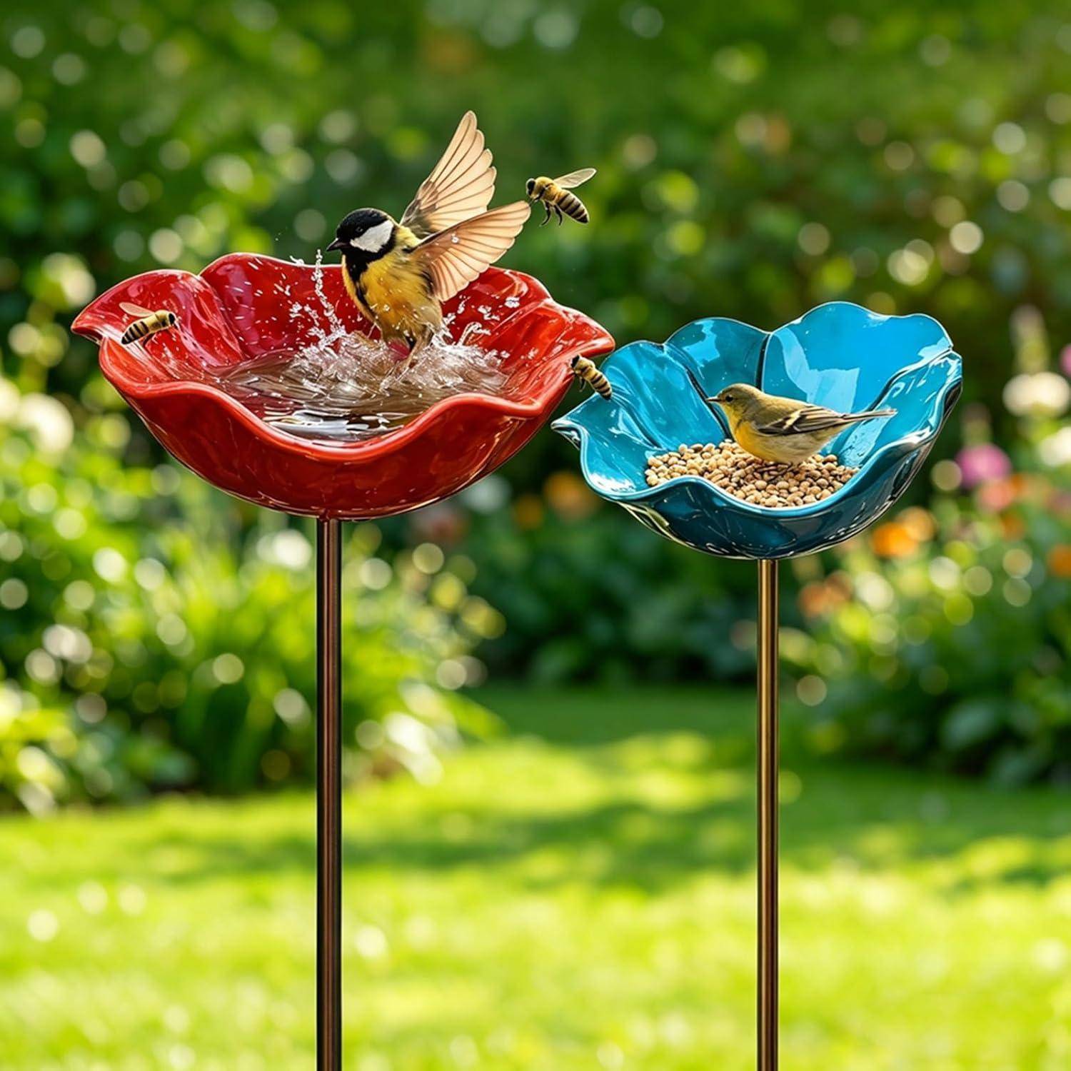Zwei Vogelfutterhäuser auf Pfosten in einem Garten, eine rote Wasserschale mit spritzenden Vögeln und eine blaue Samenschale mit einem fressenden Vogel, mit Bienen in der Nähe.
