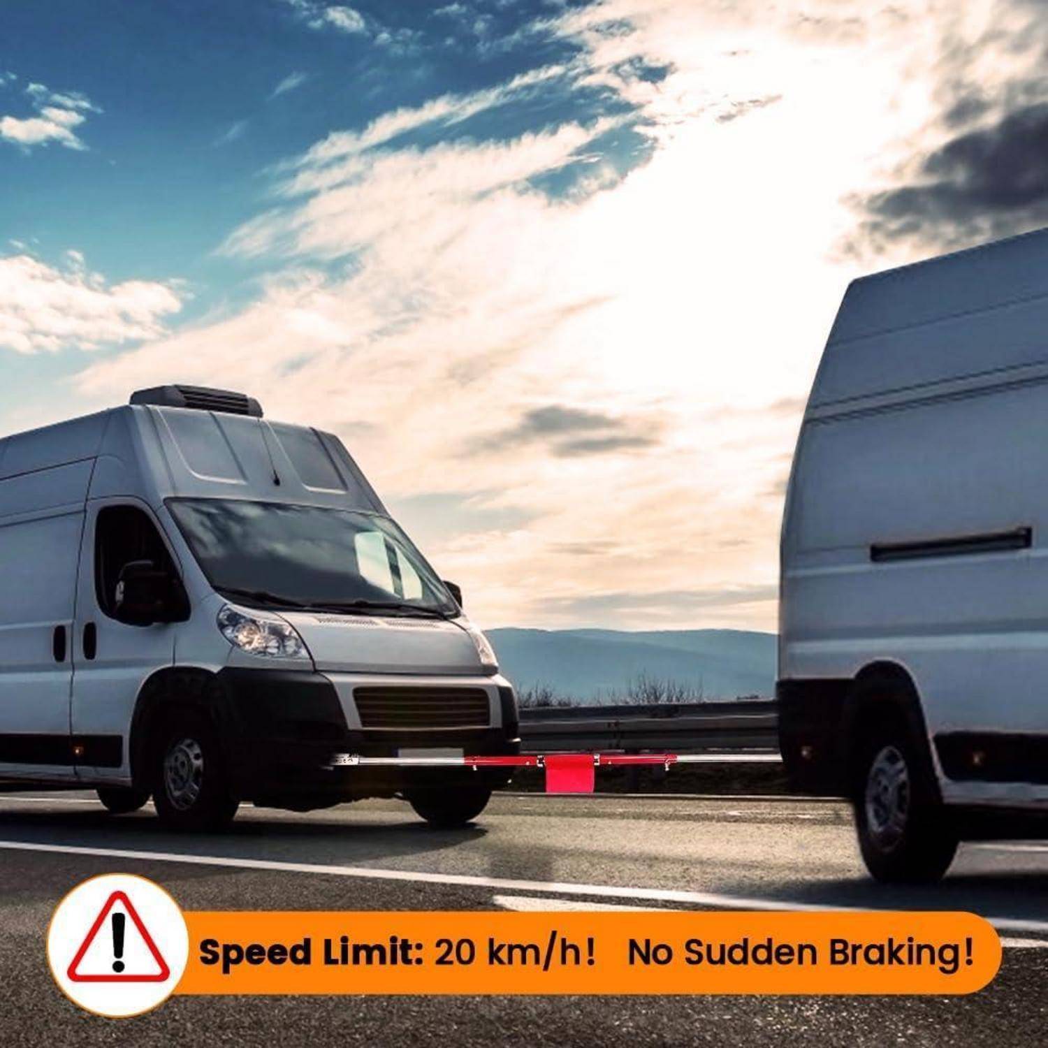 Zwei weiße Transporter sind auf einer Straße durch eine Abschleppstange verbunden, mit einem Warnbanner, auf dem steht: „Geschwindigkeitsbegrenzung: 20 km/h! Keine plötzlichen Bremsungen!