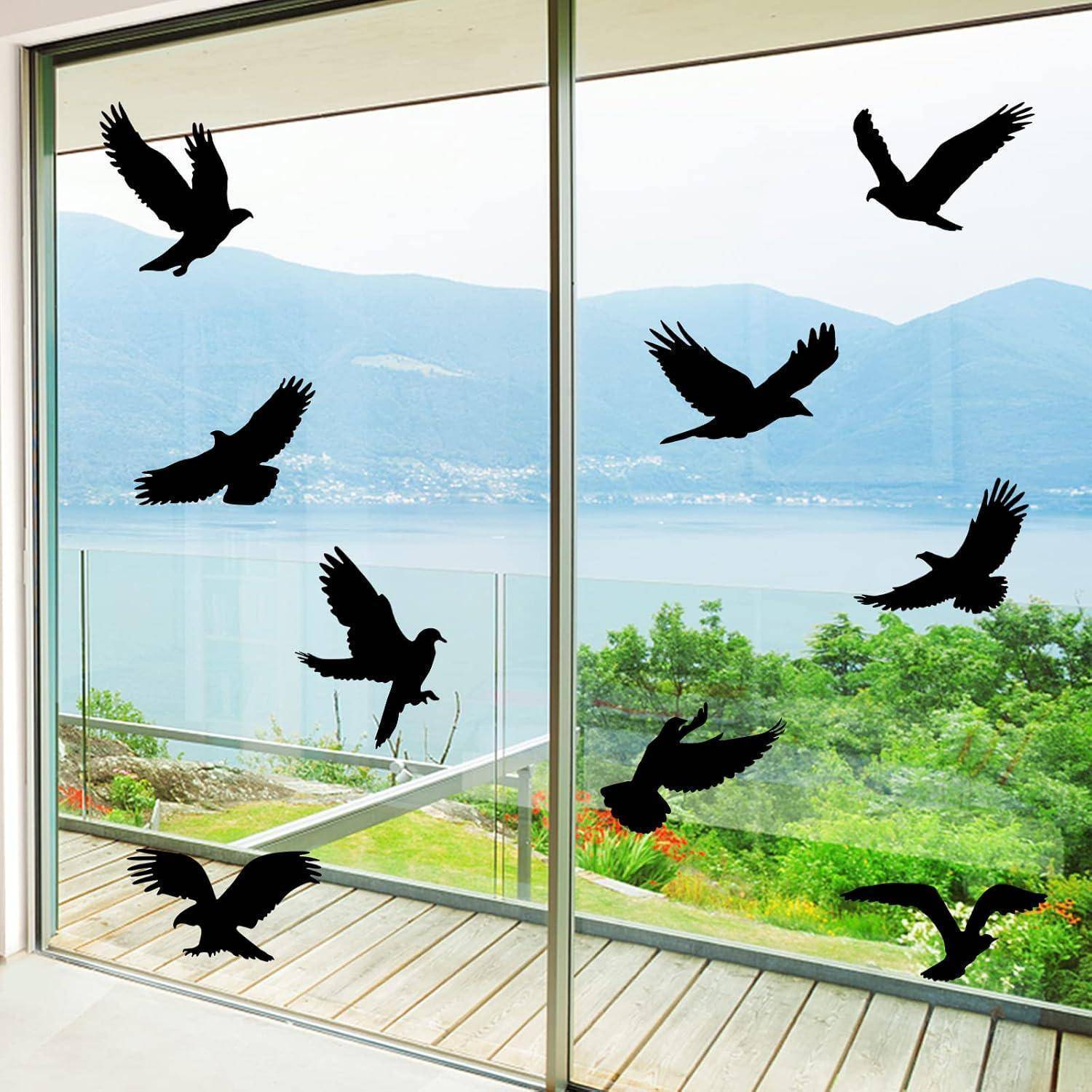 Silhouetten von fliegenden Vögeln auf großen Glastüren, mit einem See, Bergen und Grün sichtbar draußen.