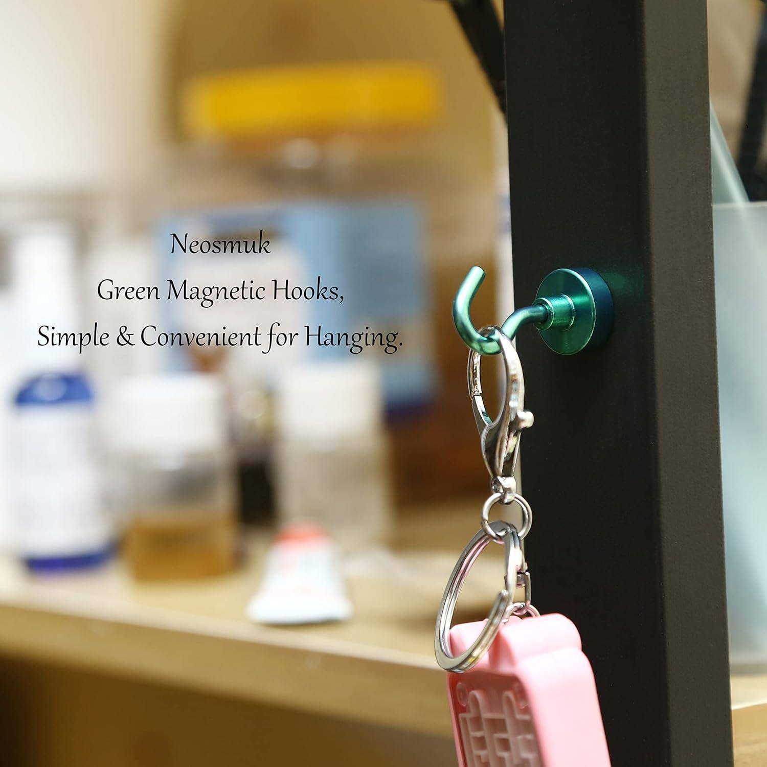 Grüner Magnetik-Haken auf einer Glaskachel hält einen Schlüsselring mit rosa Gehäuse; der Text lautet „Neosmuk Grüne Magnetik-Haken, einfach und praktisch zum Aufhängen.