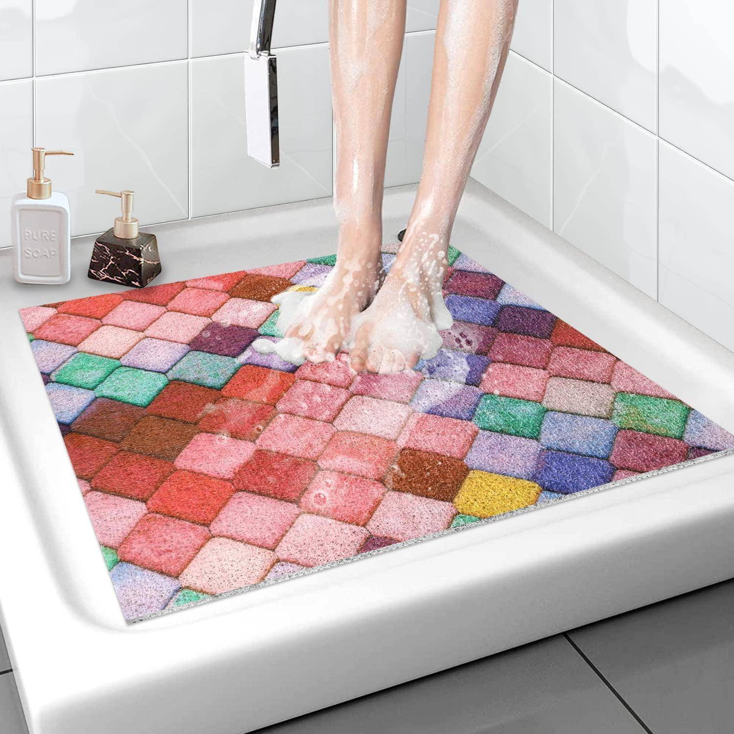 Person, die Füße in einer Dusche auf einer farbenfrohen geometrischen Badmatte in einer weiß gefliesten Kabine wäscht.