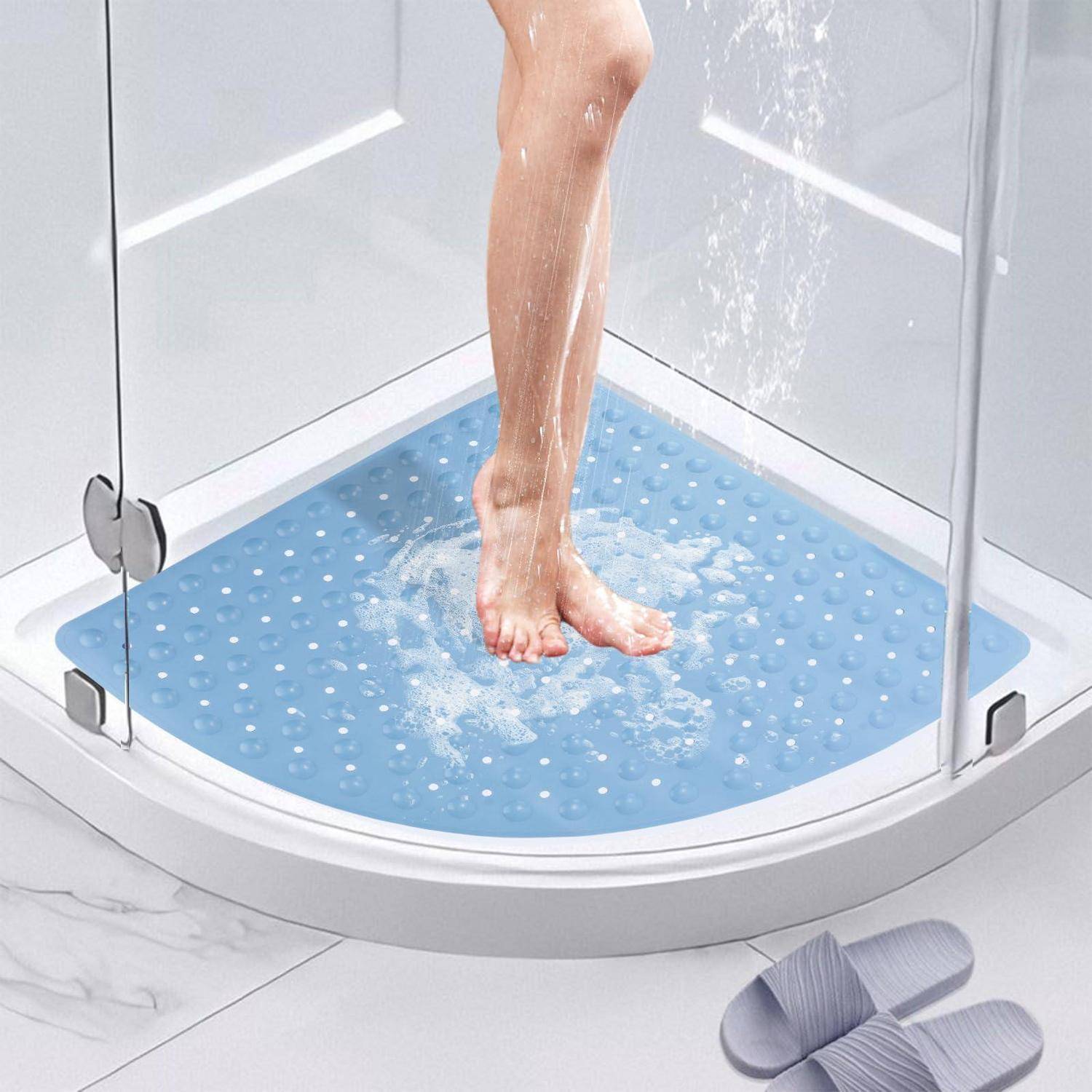 Person, der in einer gebogenen Glaseckendusche duscht, steht auf einer blauen rutschfesten Matte mit Wasser, das auf dem Boden spritzt.
