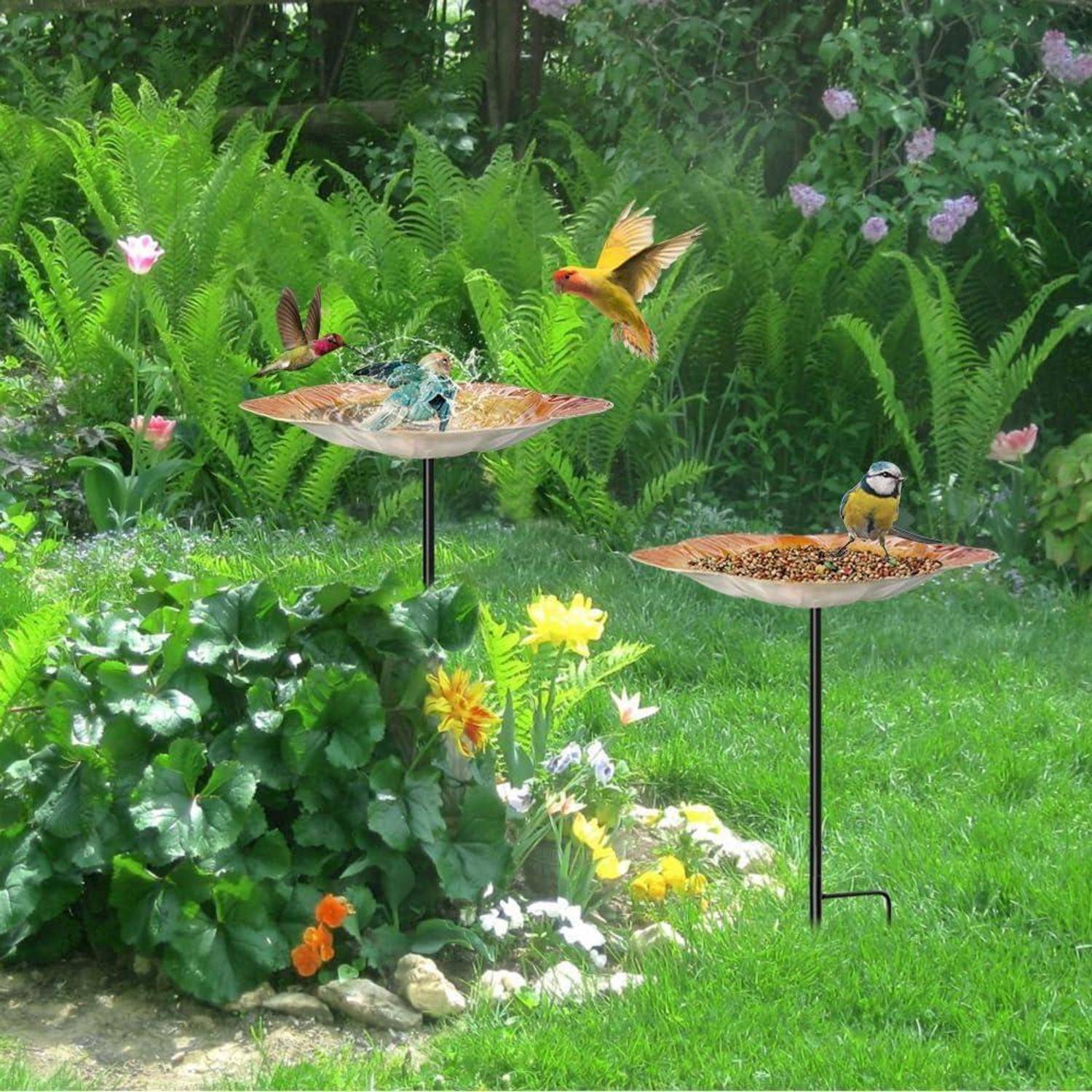 Zwei Vogelfutterstellen in einem üppigen Garten, mit mehreren Vögeln, die auf ihnen sitzen und um sie herum fliegen.