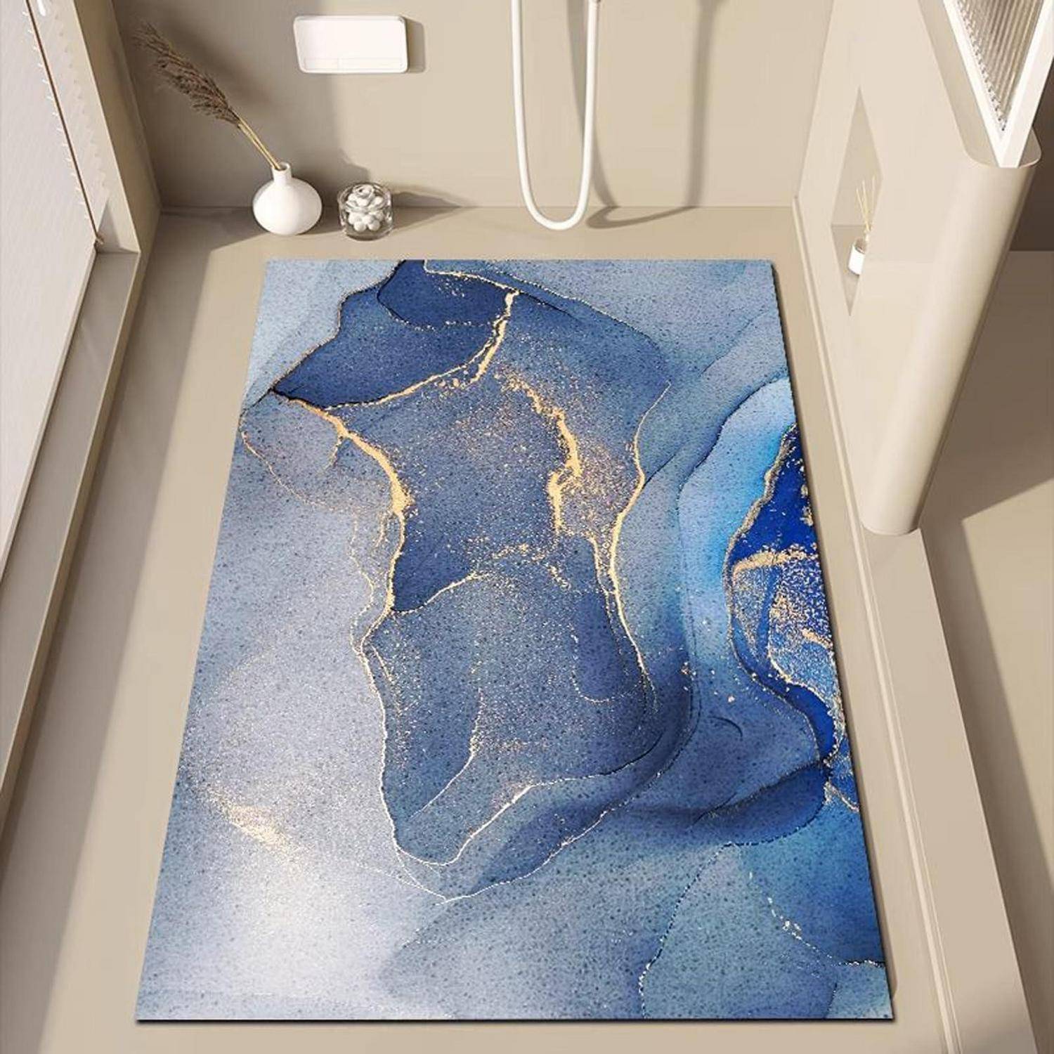 Blauer abstrakter Teppich mit goldfarbenen Adern, in einem beigen Badezimmer neben einer Toilette und einem Waschbecken gezeigt.