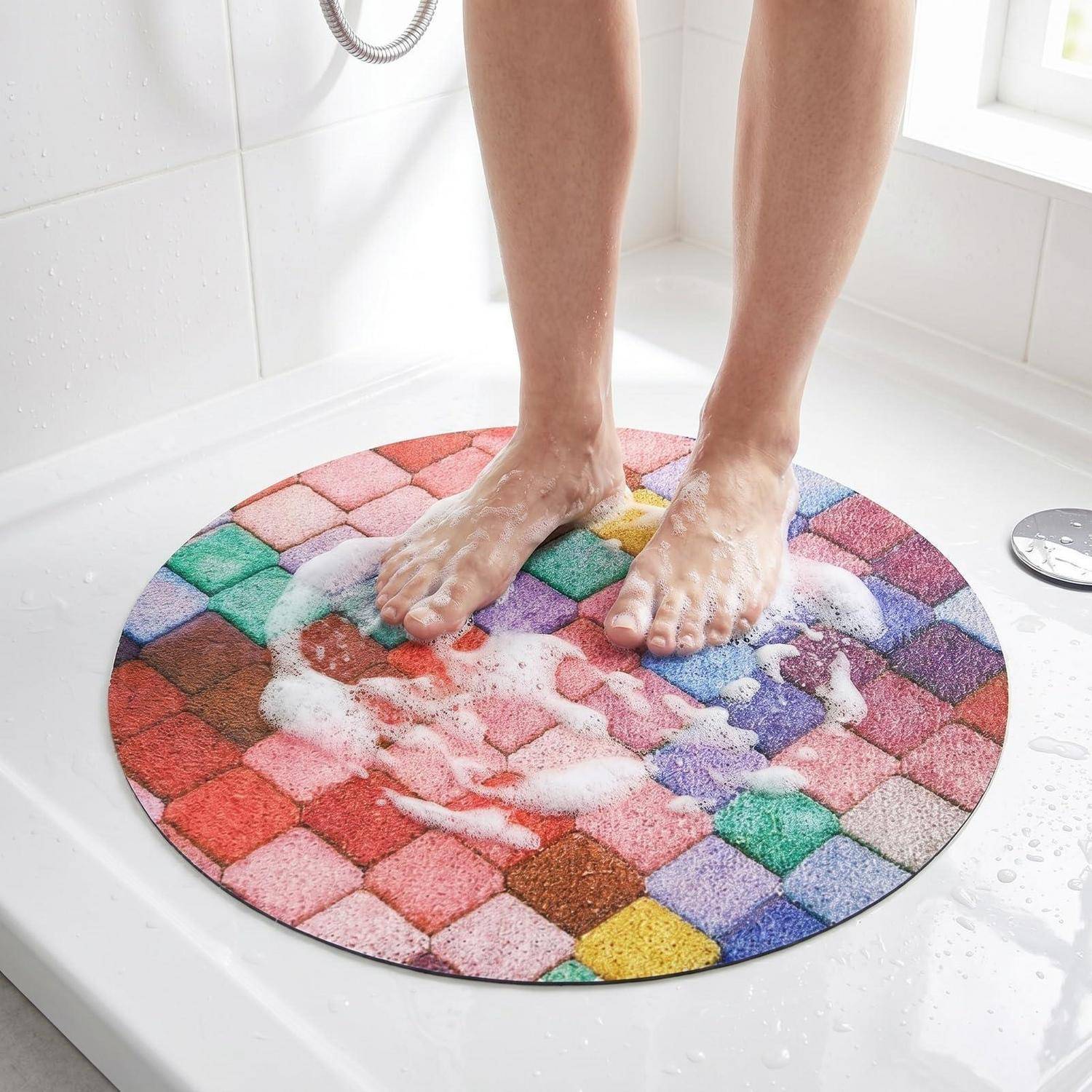 Eine Person, die auf einer bunten runden Badematte in einer Dusche steht und sich die Füße wäscht, mit Seifenschaum und nassem Fliesenboden.