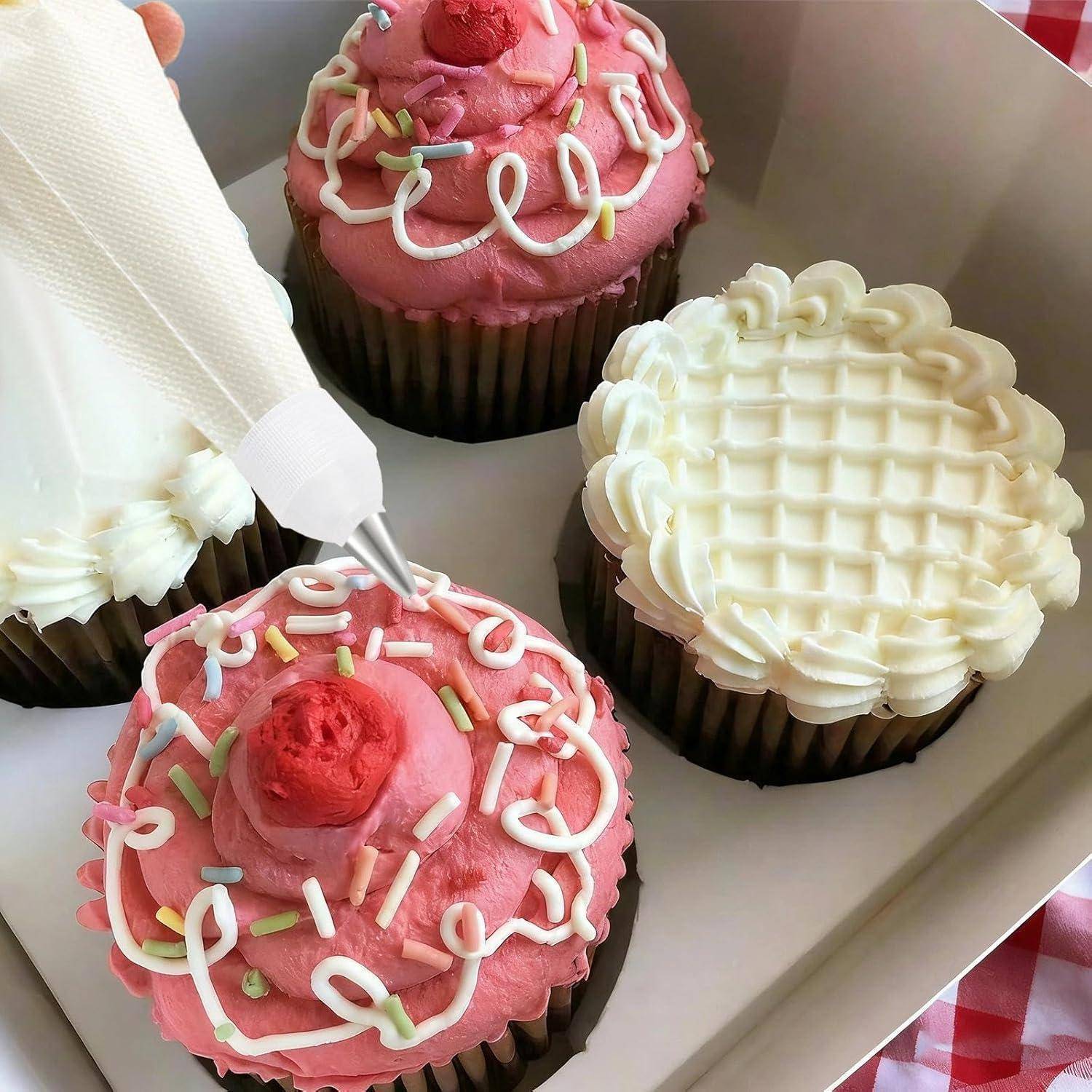 Schachtel mit verzierten Cupcakes mit rosa Frosting und weißem Zuckerguss; ein Cupcake wird gerade mit Frosting aus einem Spritzbeutel verziert