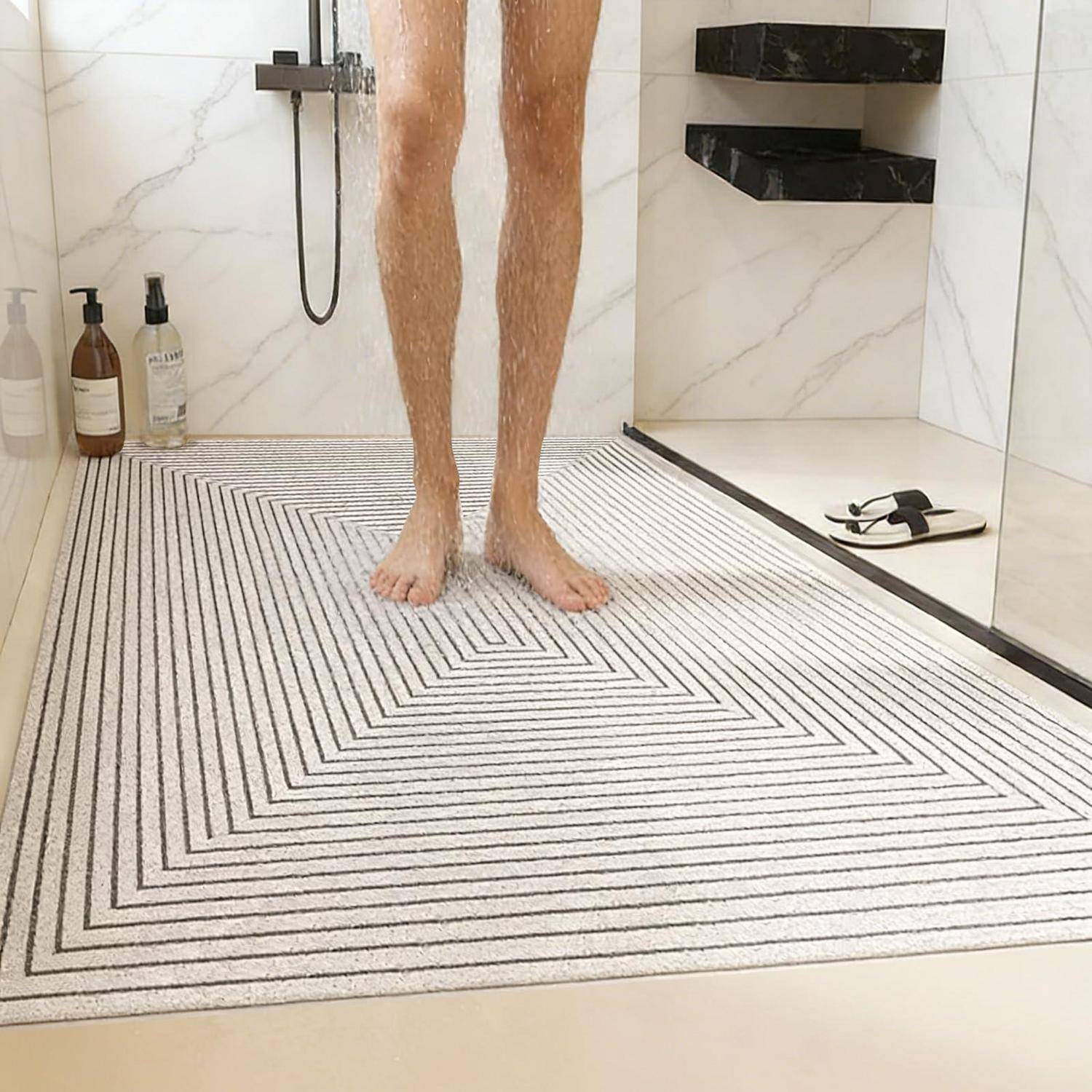 Person, die barfuß in einer Dusche steht, mit Wasser, das auf eine gemusterte Badmatte in einem gekachelten Badezimmer fließt.