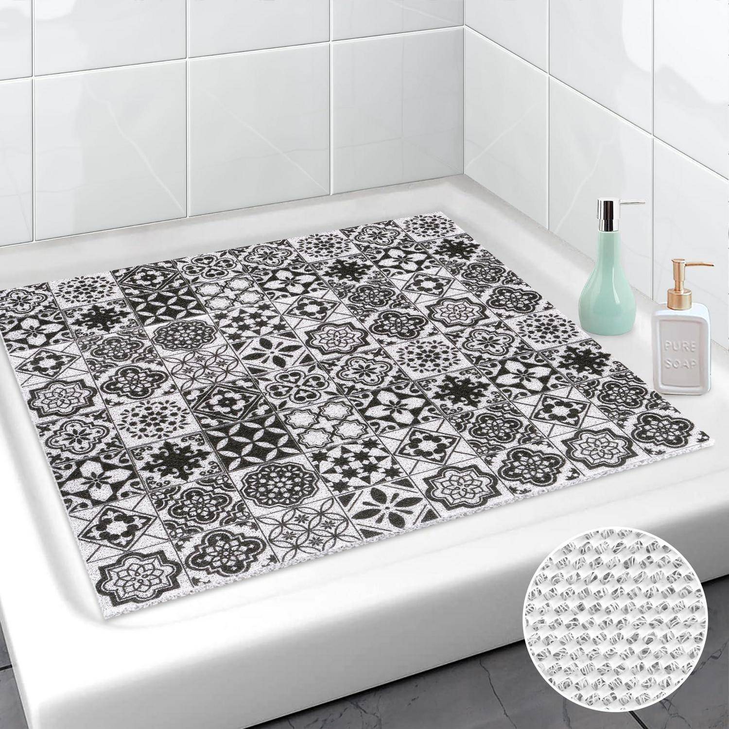 Schwarzweiß gemusterter Badematte in einer Dusche oder Badewanne, gezeigt in einer Badezimmerecke mit Seifenspender und Flasche; Ausschnitt hebt die strukturierte Unterseite hervor.