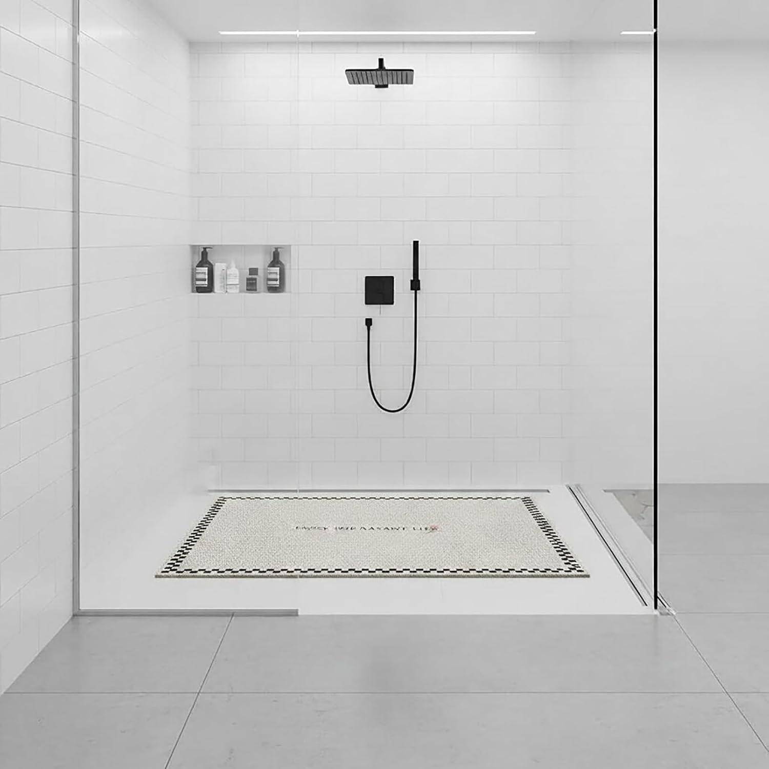 Minimalistische begehbare Dusche in Weiß mit schwarzen Armaturen, Wandnischen-Flaschen und einer gemusterten Bodenmatte in einer Glasumhausung.