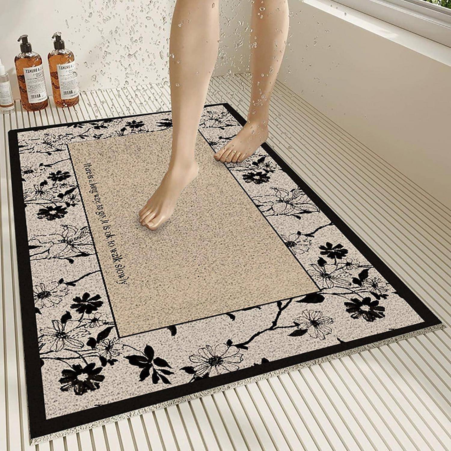Schaufensterpuppenbeine, die auf einer beigen Badematte mit Blumenmuster in einem Badezimmer stehen, neben zwei Pumpflaschen auf einem Sims.