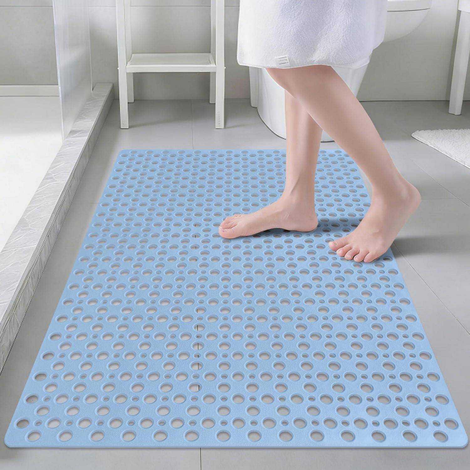 Nackte Füße, die auf einer hellblauen perforierten Badmatte in einem Badezimmer stehen, was eine rutschfeste Oberfläche andeutet