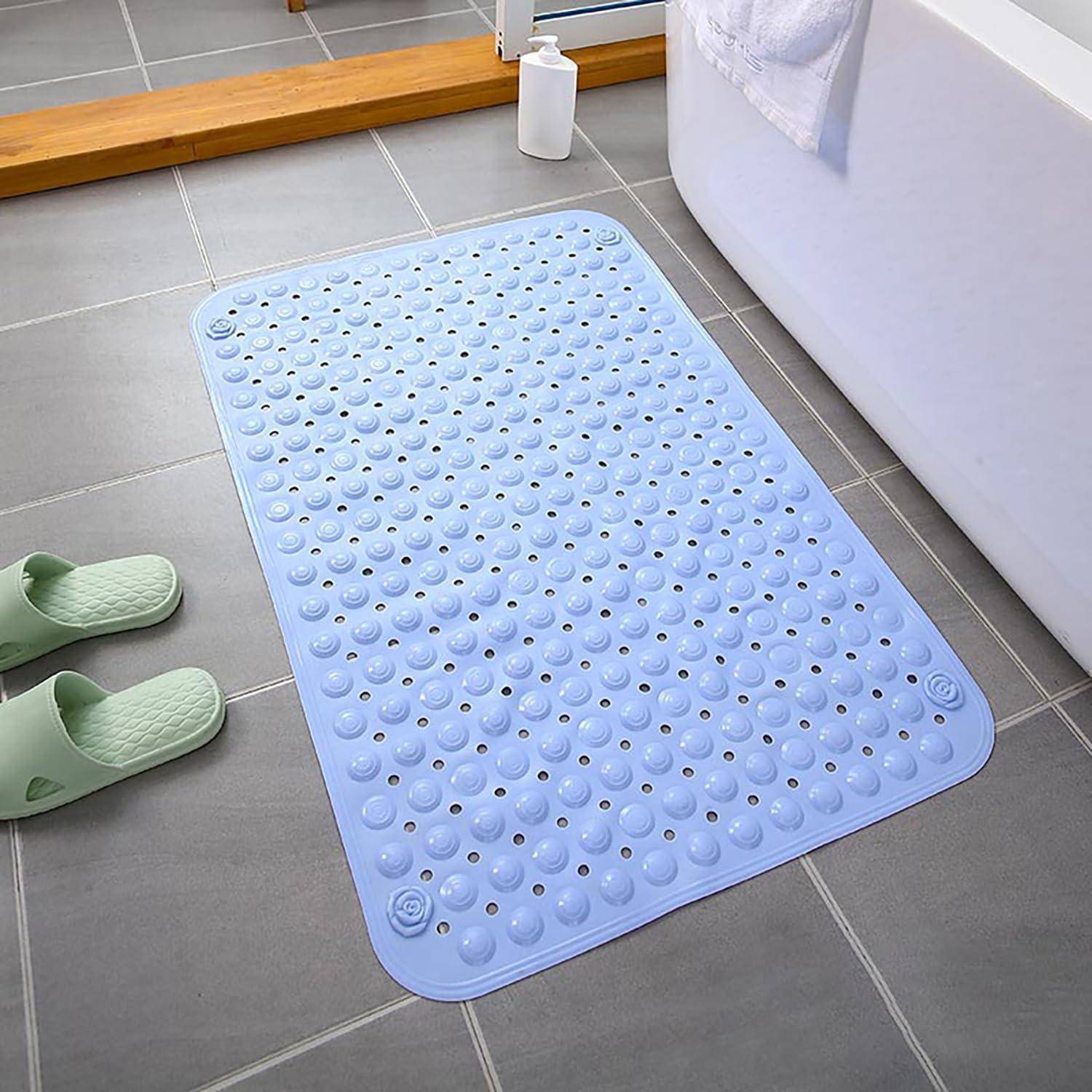 Hellblaubraue Badmatte auf grauem Fliesenboden im Badezimmer neben einer Badewanne, mit grünen Pantoffeln und einer Flasche im Hintergrund.
