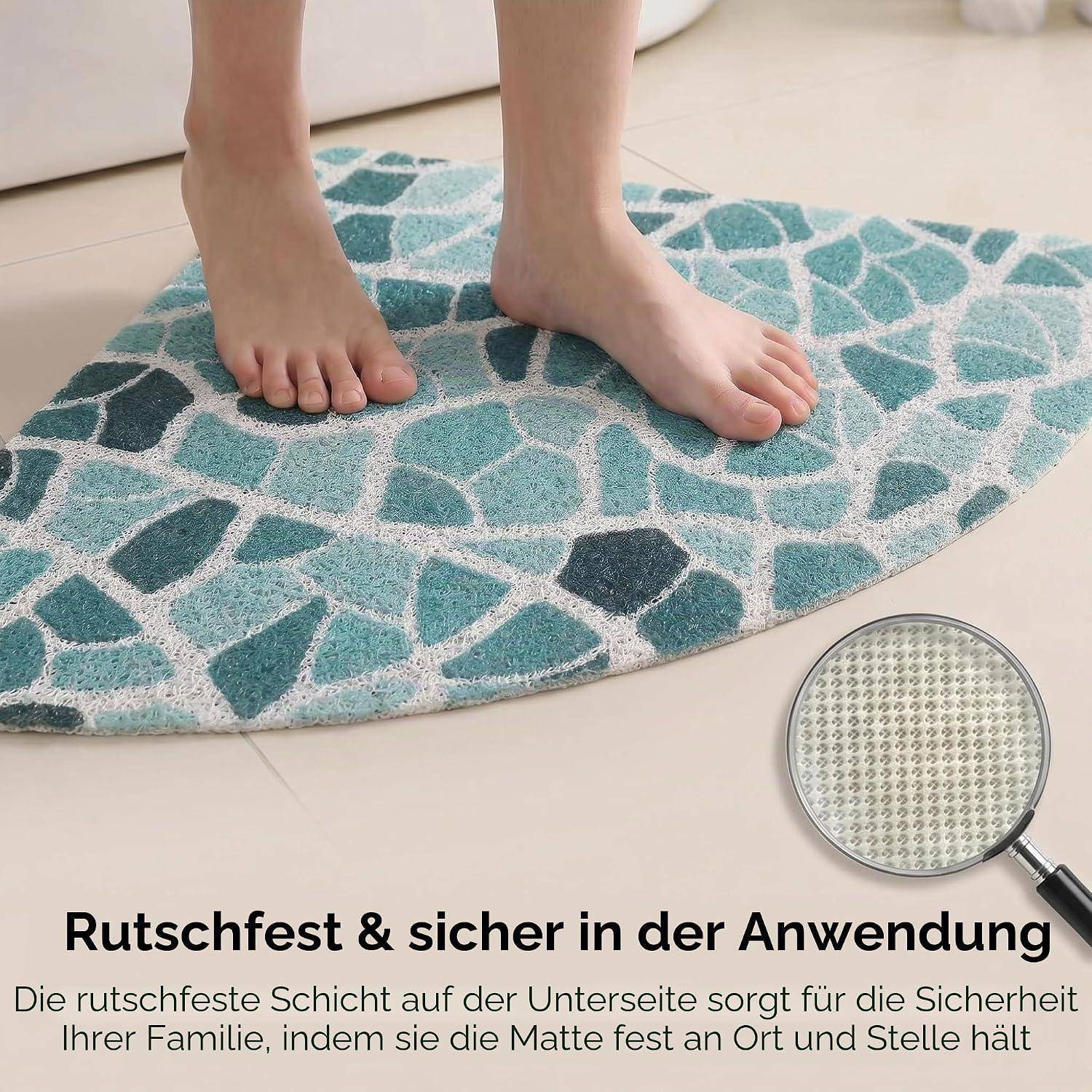 Nackte Füße, die auf einer blaugrünen gemusterten Badmatte stehen, mit deutschem Text darunter, der besagt, dass sie rutschfest und sicher zu verwenden ist.