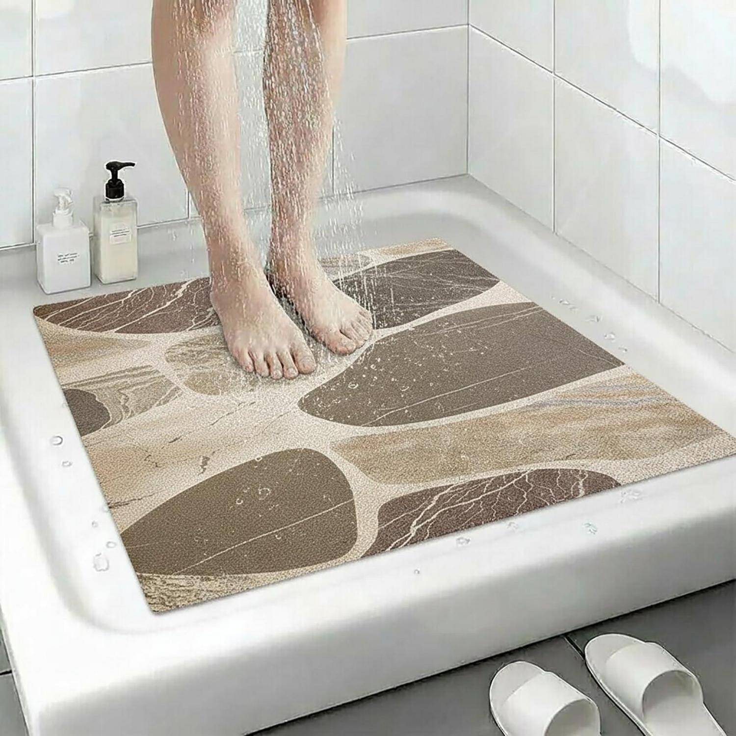 Person, die unter der Dusche in einer Badewanne steht, auf einer gemusterten rutschfesten Badewannenmatte stehend.