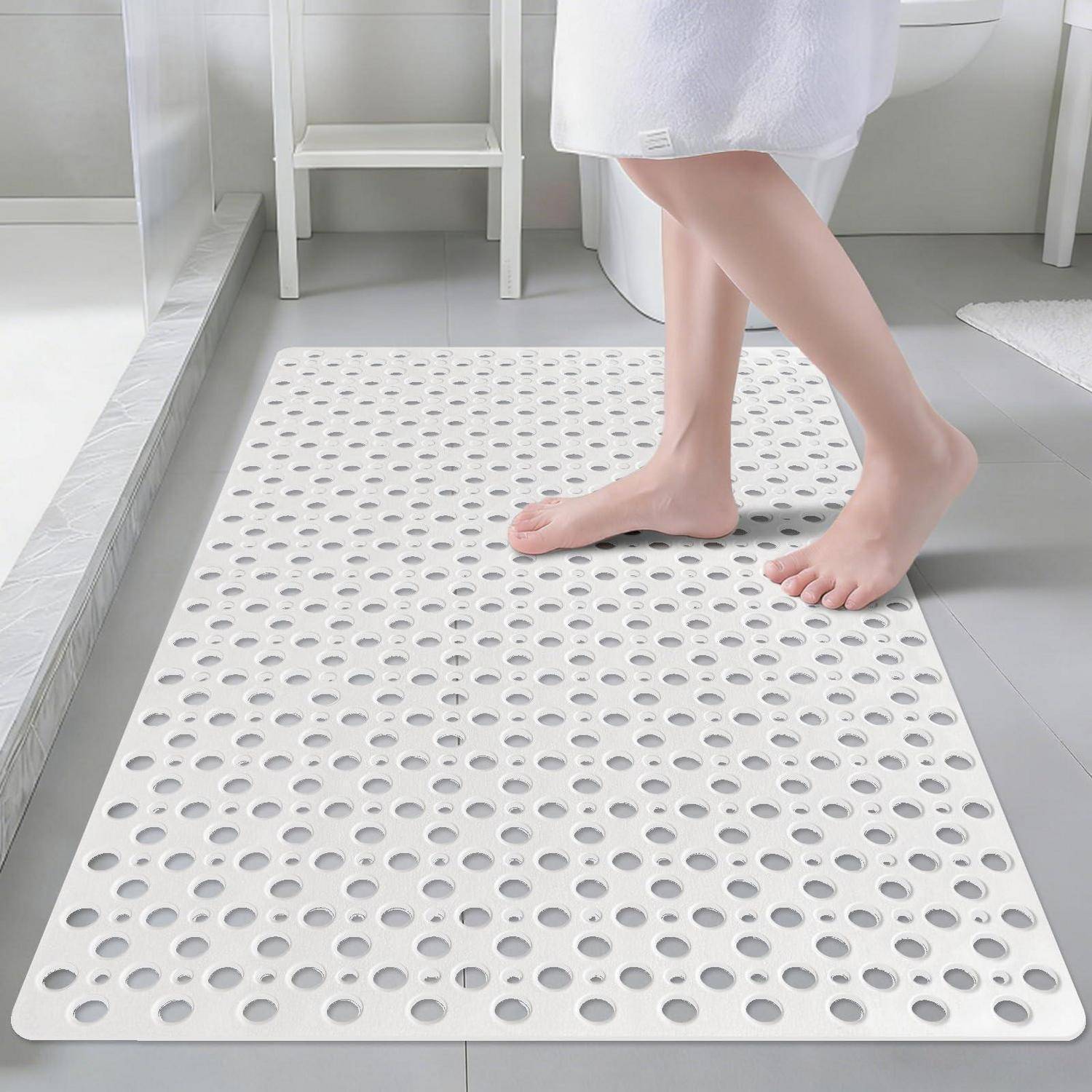 Nackte Füße auf einer weißen perforierten Badewanne in einem Badezimmer, gezeigt neben einem Waschbecken und Spiegel.