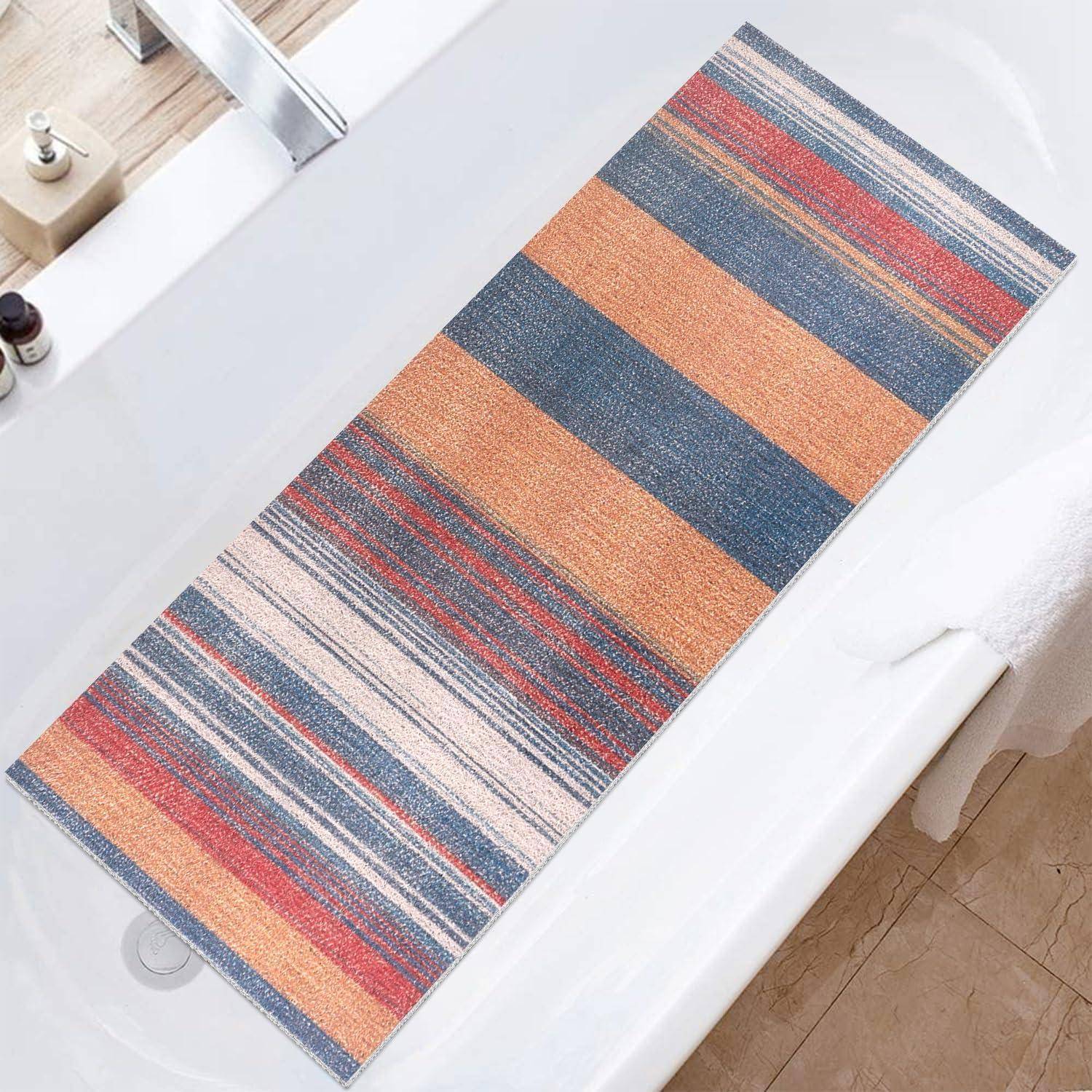 Gestreifter rechteckiger Webbadeteppich in Blau, Orange, Rot und Creme auf einem weißen Badezimmerboden neben einer Badewanne.