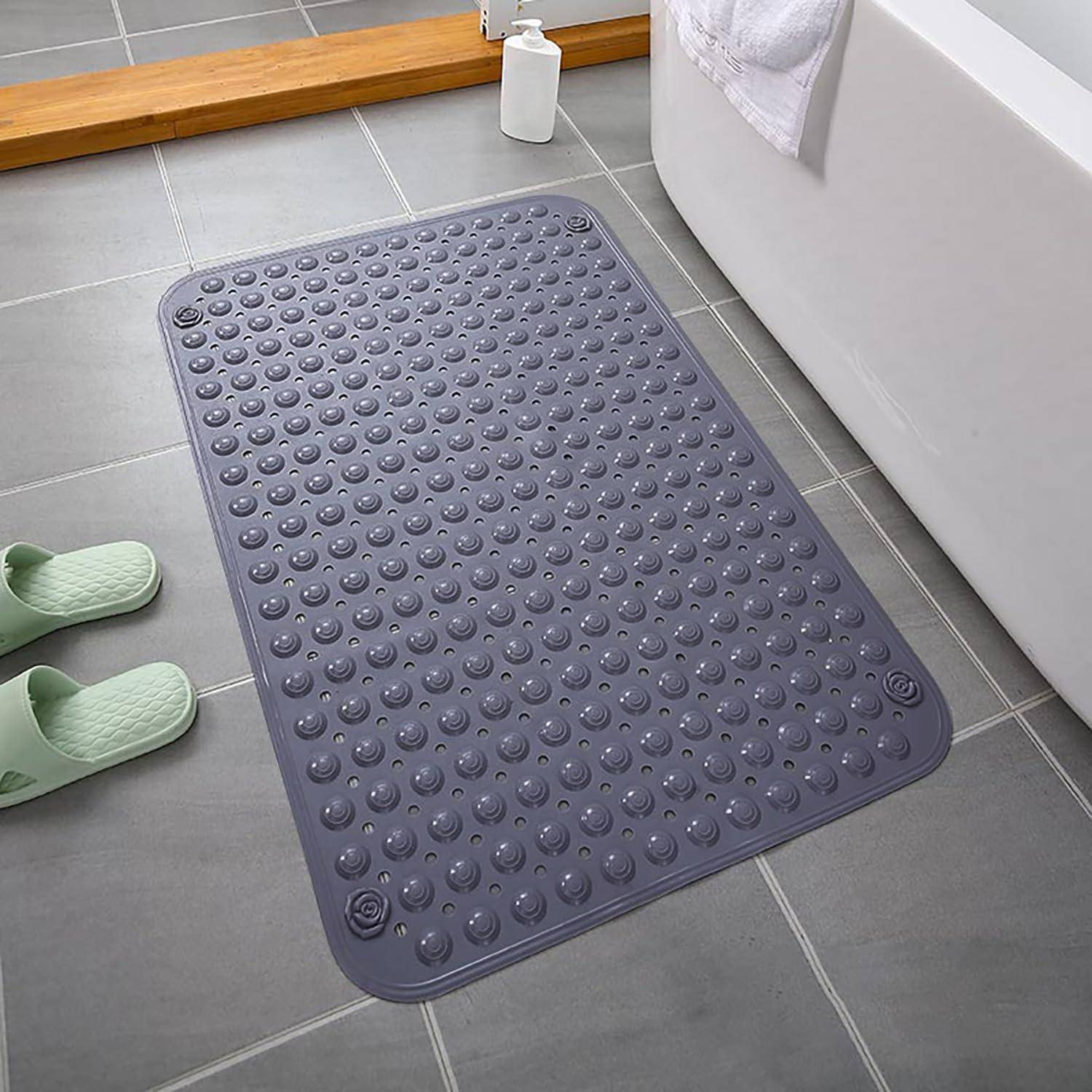 Violette rutschfeste Badewannenmatte mit erhabenen Saugnapfpunkten auf einem gekachelten Badezimmerboden neben einer Wanne und Hausschuhen.