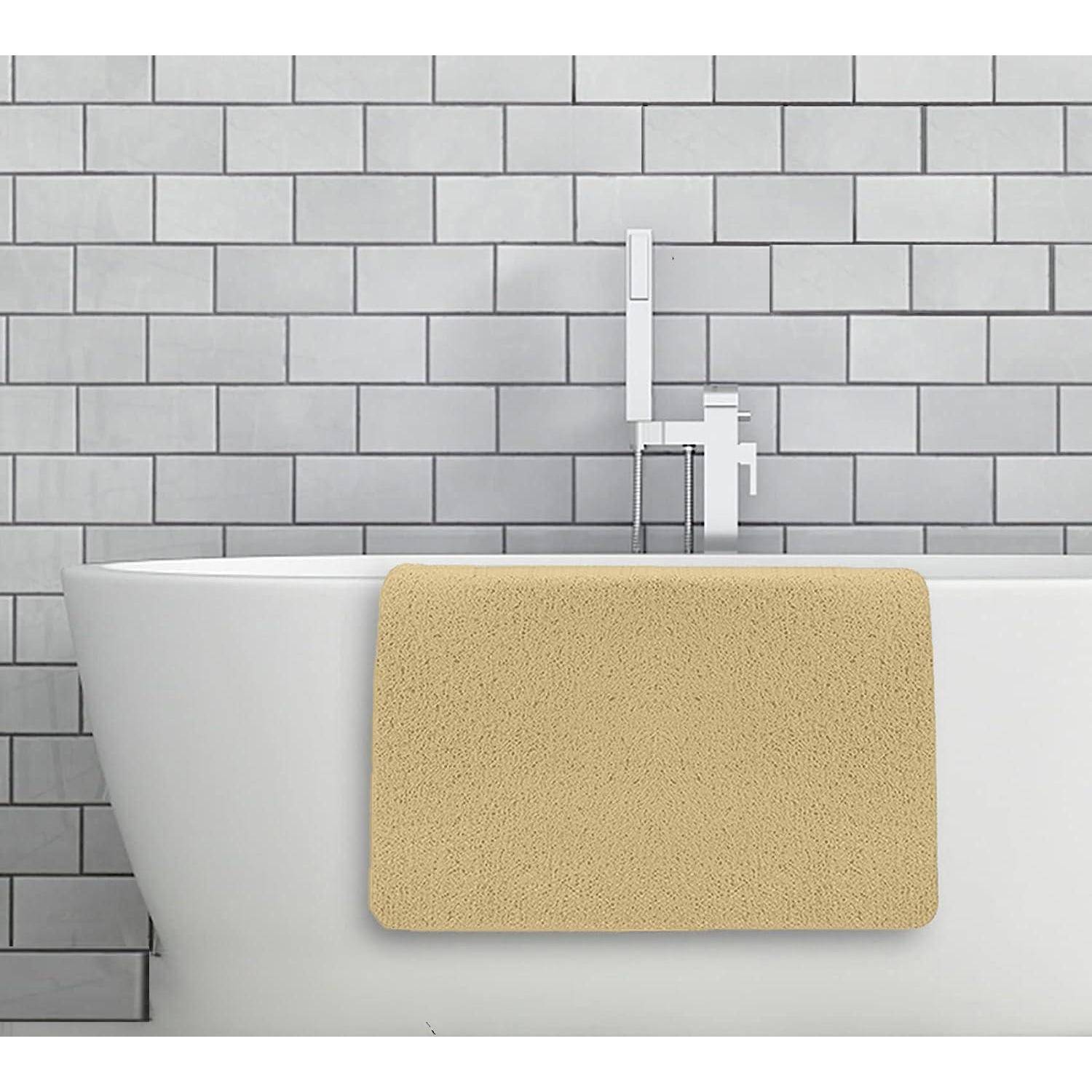 Weiße Badewanne vor einer grauen gefliesten Wand mit einer beigen Badematte, die über die Vorderseite drapiert ist, und einem modernen Wasserhahn dahinter.