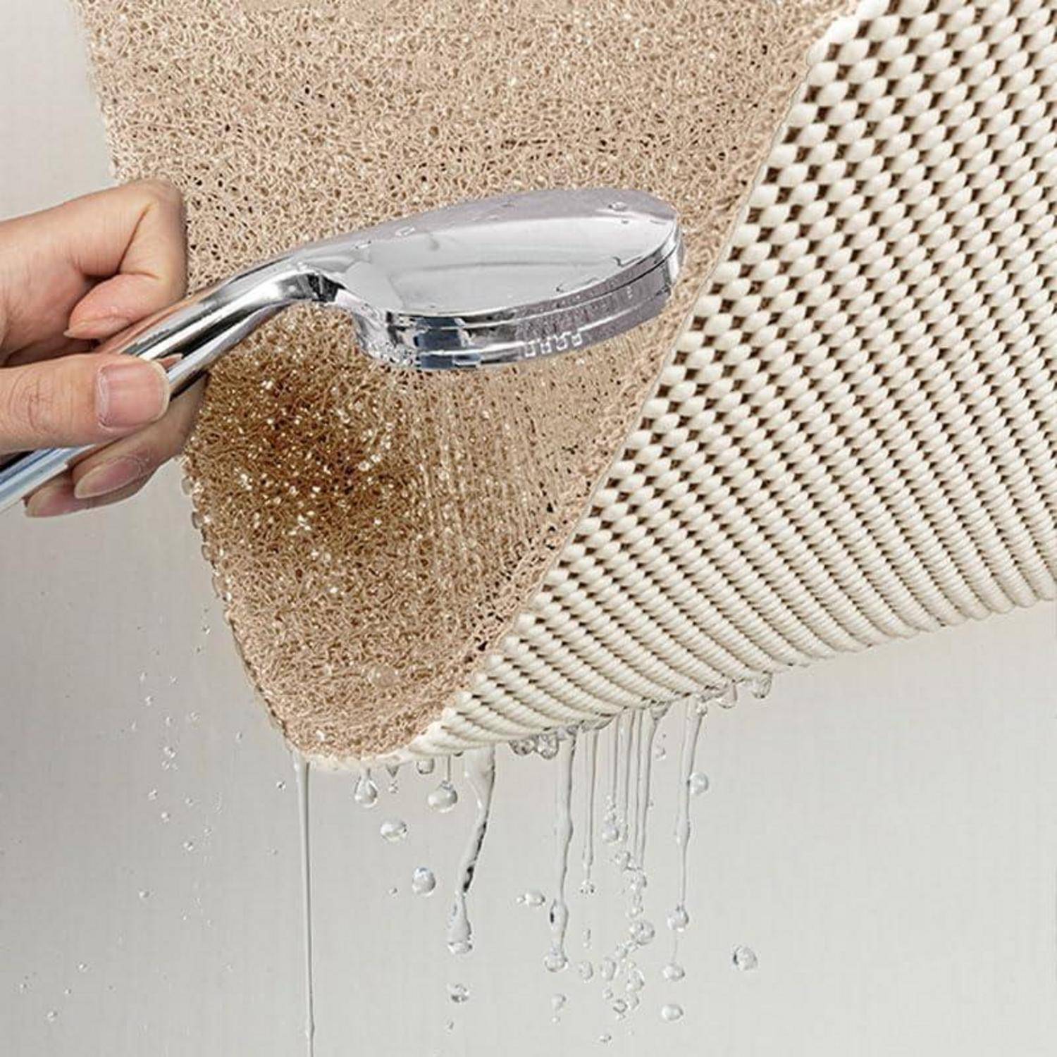 Handbrause spült eine strukturierte beige und weiße Matte ab und zeigt, wie Schmutz abgewaschen wird und Wasser von der Oberfläche tropft.