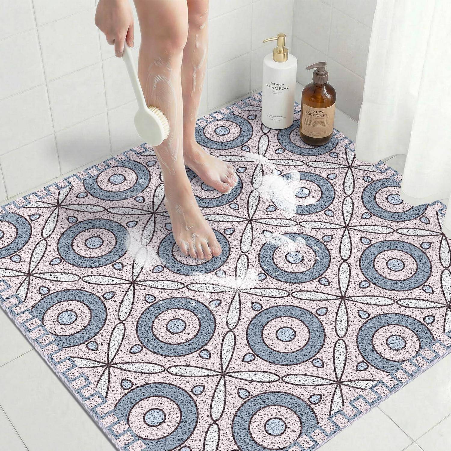 Füße werden mit einer Duschbürste auf einer gemusterten Badmatte in einem Dusch- oder Badbereich abgespült, mit Shampoo- und Seifenflaschen in der Nähe.