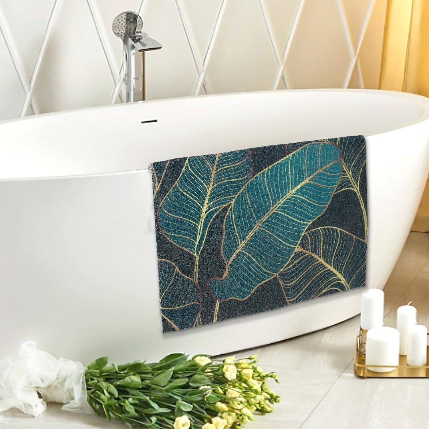 Eine moderne weiße Badewanne mit einem Handtuch mit Blattmuster darüber geworfen, Blumen auf dem Boden und Kerzen daneben in einem hellen Badezimmer.