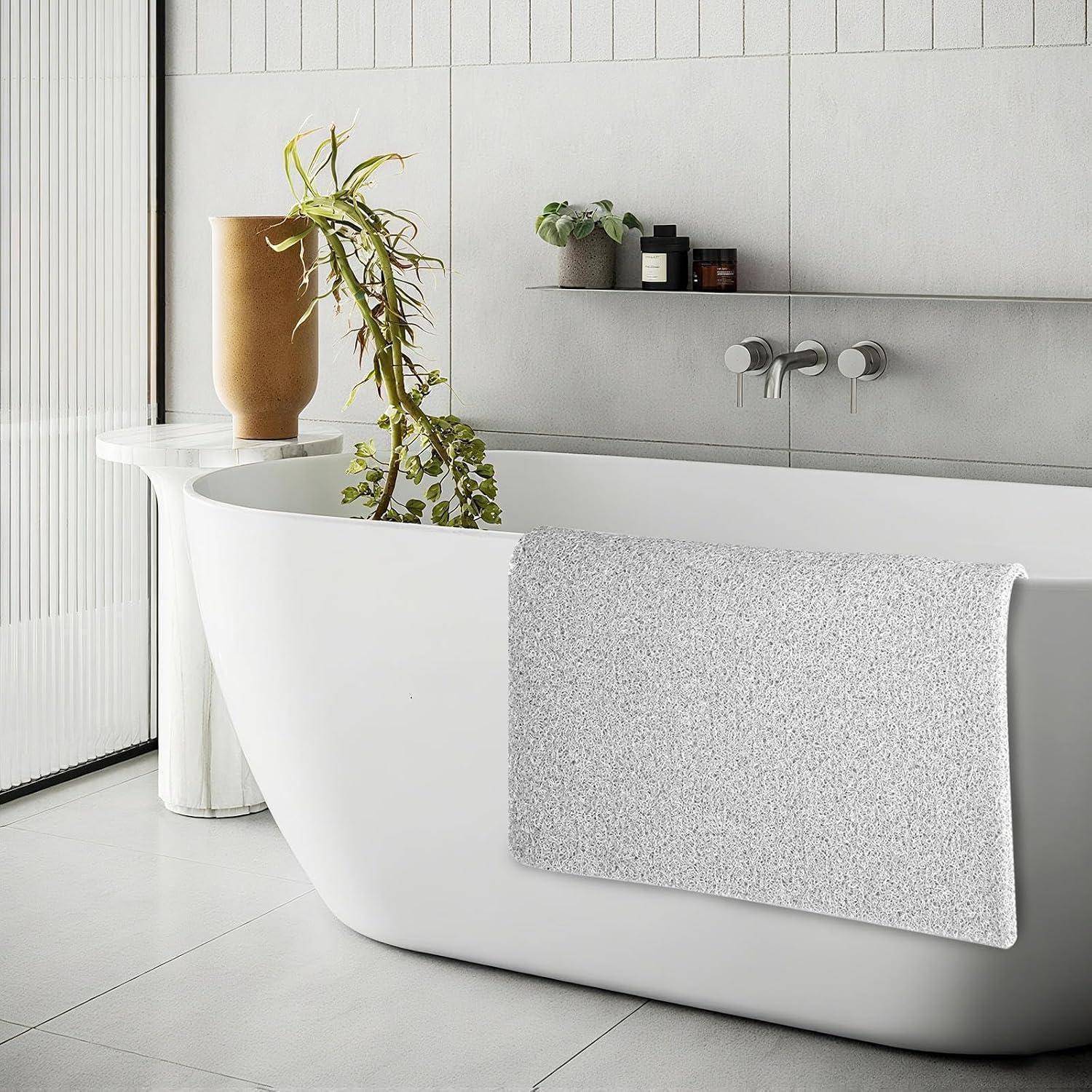Modernes Badezimmer mit freistehender weißer Badewanne, strukturiertem grauem Handtuch, Topfpflanze und minimalistischem Wandregal neben einer großen Vase.