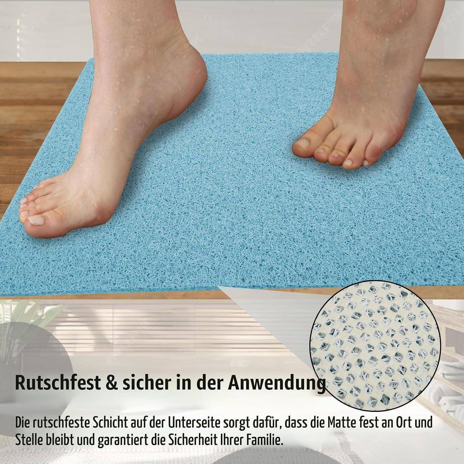 Füße stehen auf einer blauen Badematte; Die Einfügung zeigt die rutschfeste Unterseite. Der deutsche Text besagt, dass sie rutschfest ist und sicher an ihrem Platz bleibt für die Sicherheit der Familie.