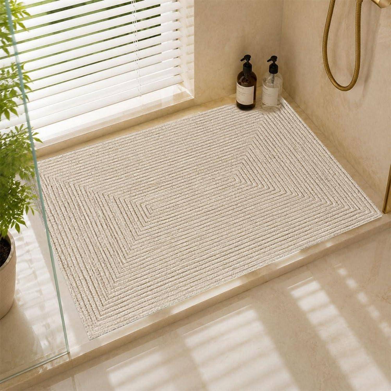 Beige Badematte mit subtiles geometrisches Muster auf einem Duschablage, neben Seifenspendern in einem sonnendurchfluteten Badezimmer.
