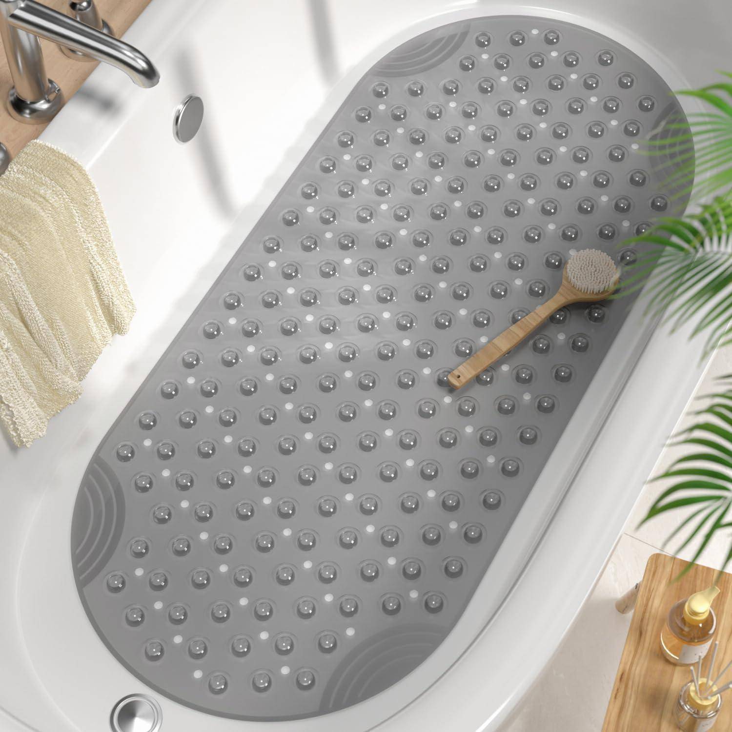 Ovale graue rutschfeste Badezimmermatte in einer Badewanne, mit einer Bürste, die darauf ruht, und Toilettenartikeln in der Nähe.