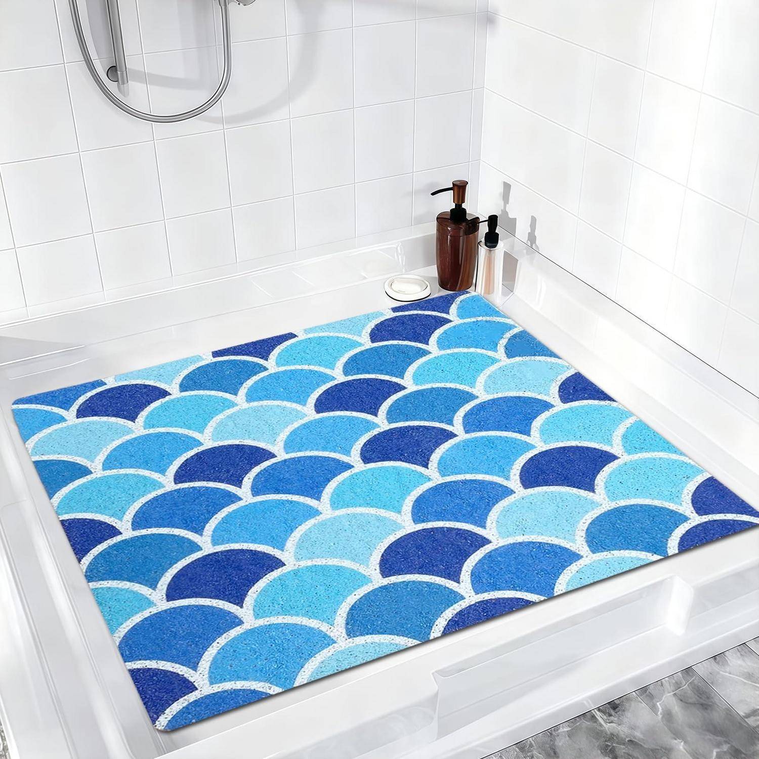 Blau-türkisfarbene Badematte mit Muschelschalenmuster in einer weißen Duschkabine mit Seifenspendern auf dem Sims.