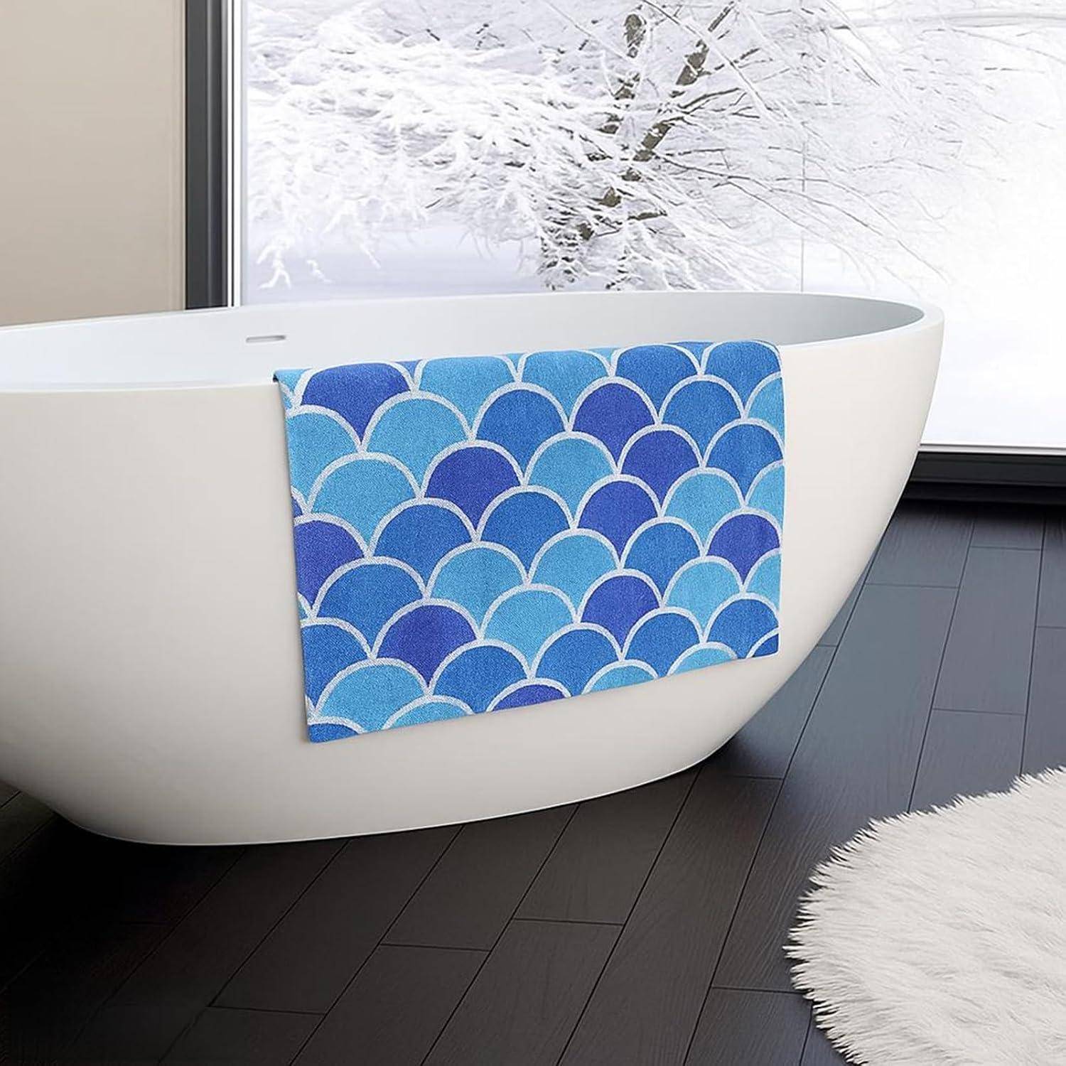 Ein blaugefiedertes Handtuch mit Fischschuppenmuster hängt über der Seite einer freistehenden weißen Badewanne in einem modernen Badezimmer.