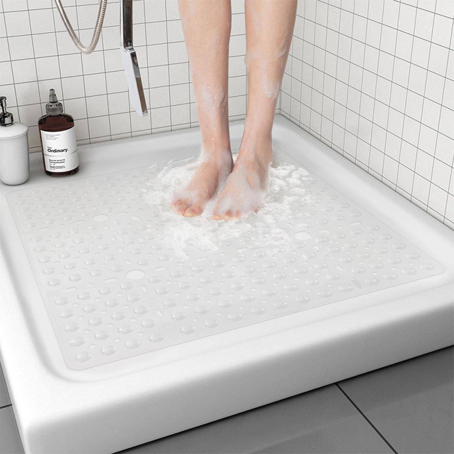Person, die auf einer strukturierten rutschfesten Duschenmatte in einer weißgefliesten Dusche steht, mit Wasser und Seifenschaum um ihre Füße.
