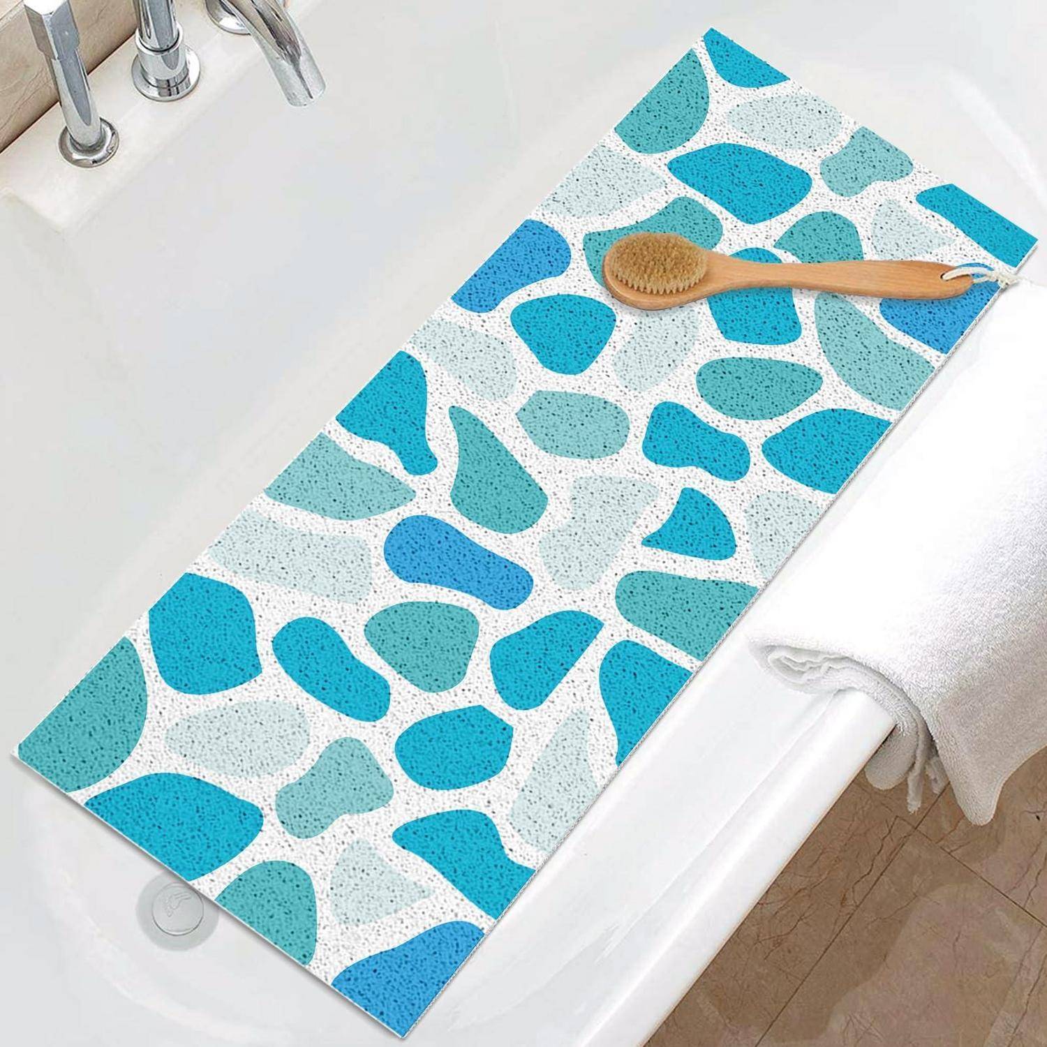 Blau-weißer Badvorleger mit Kieselsteinmuster am Rand einer Badewanne, mit einer Holzbürste oben drauf.