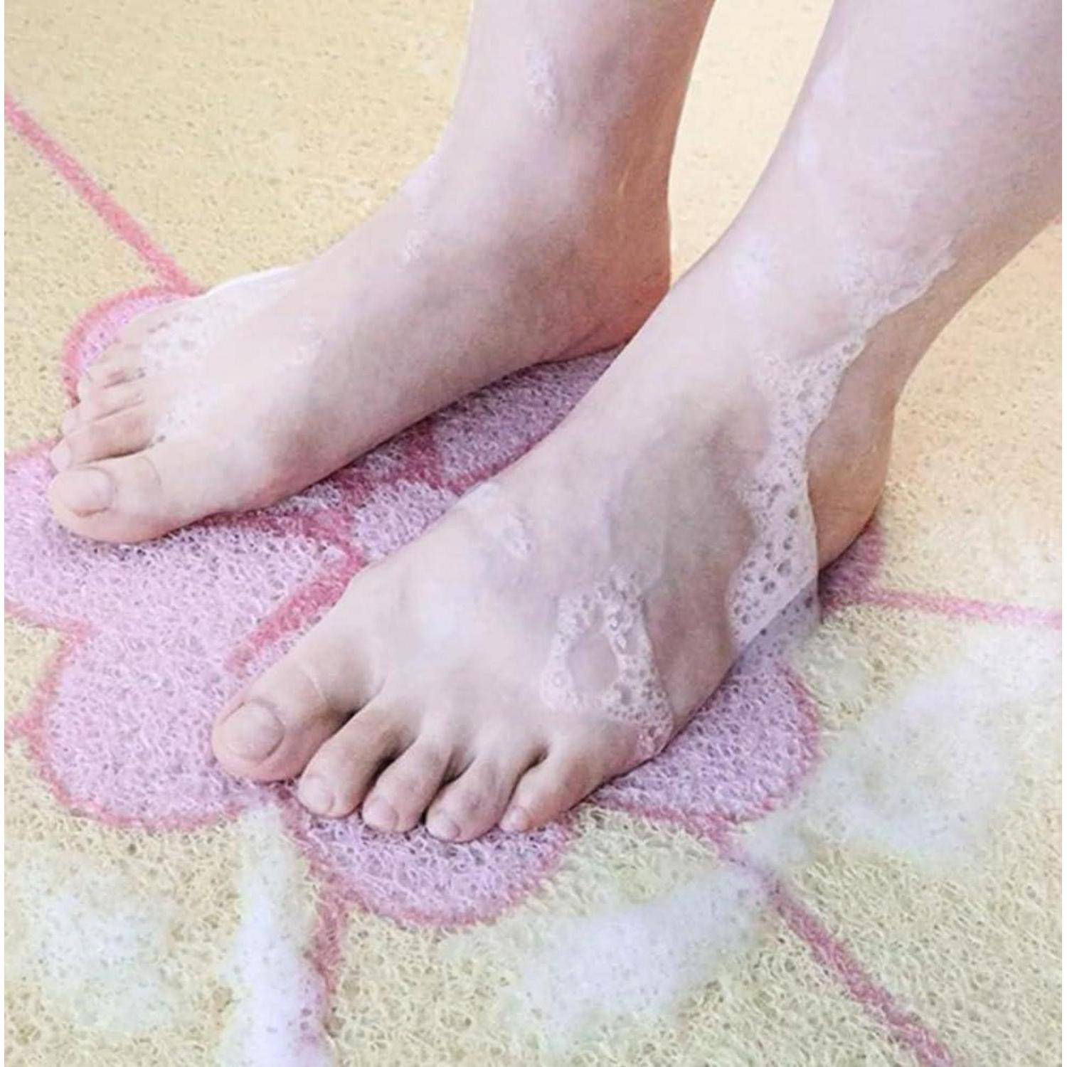Füße, die auf einem rosa Kreidef-Blumendesign auf einem strukturierten Boden stehen, mit spitzenverziertem Fußschmuck oder Socken um die Knöchel.