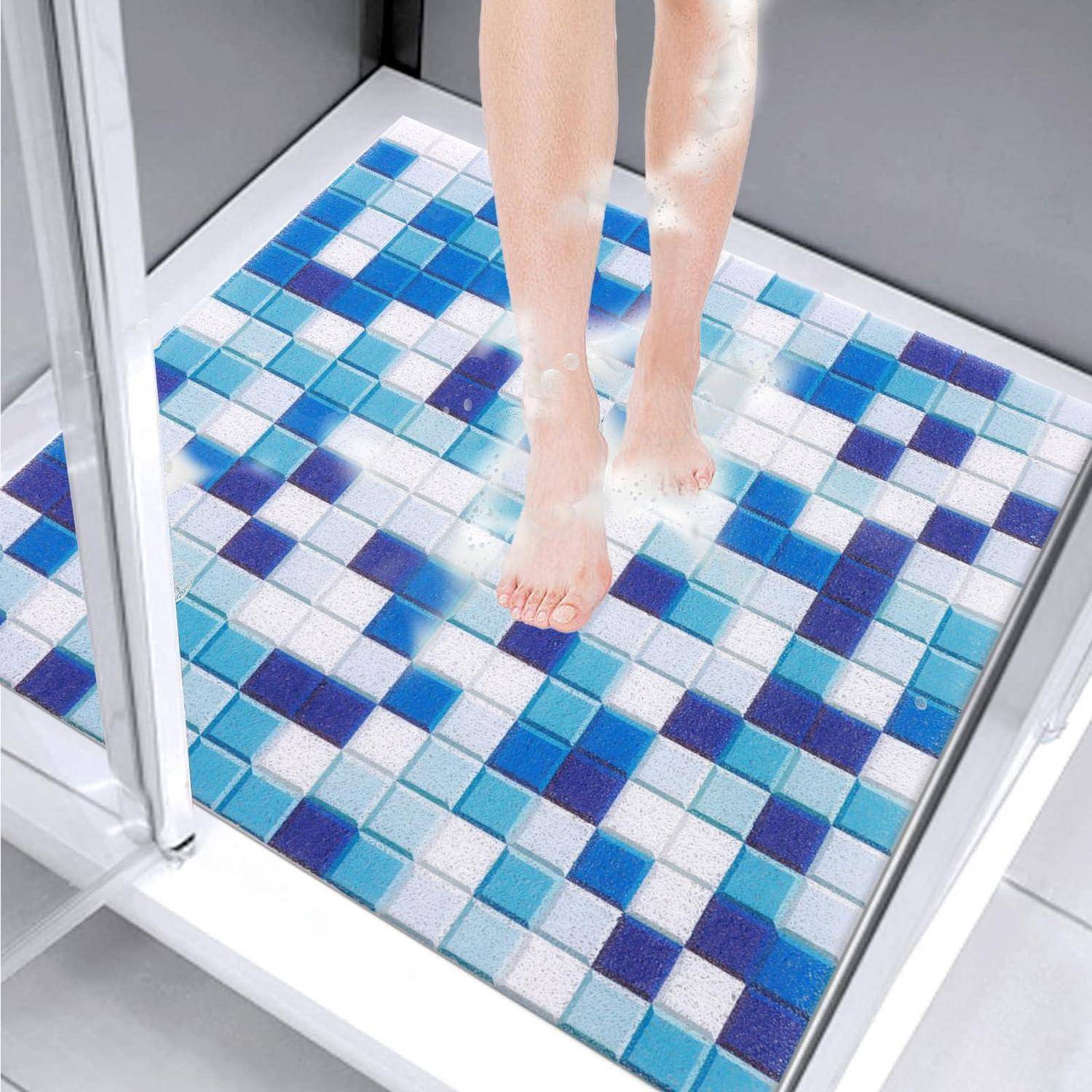Eine Person steht unter der Dusche auf einer blau-weißen Mosaik-Badmatte in einer gläsernen Duschkabine.