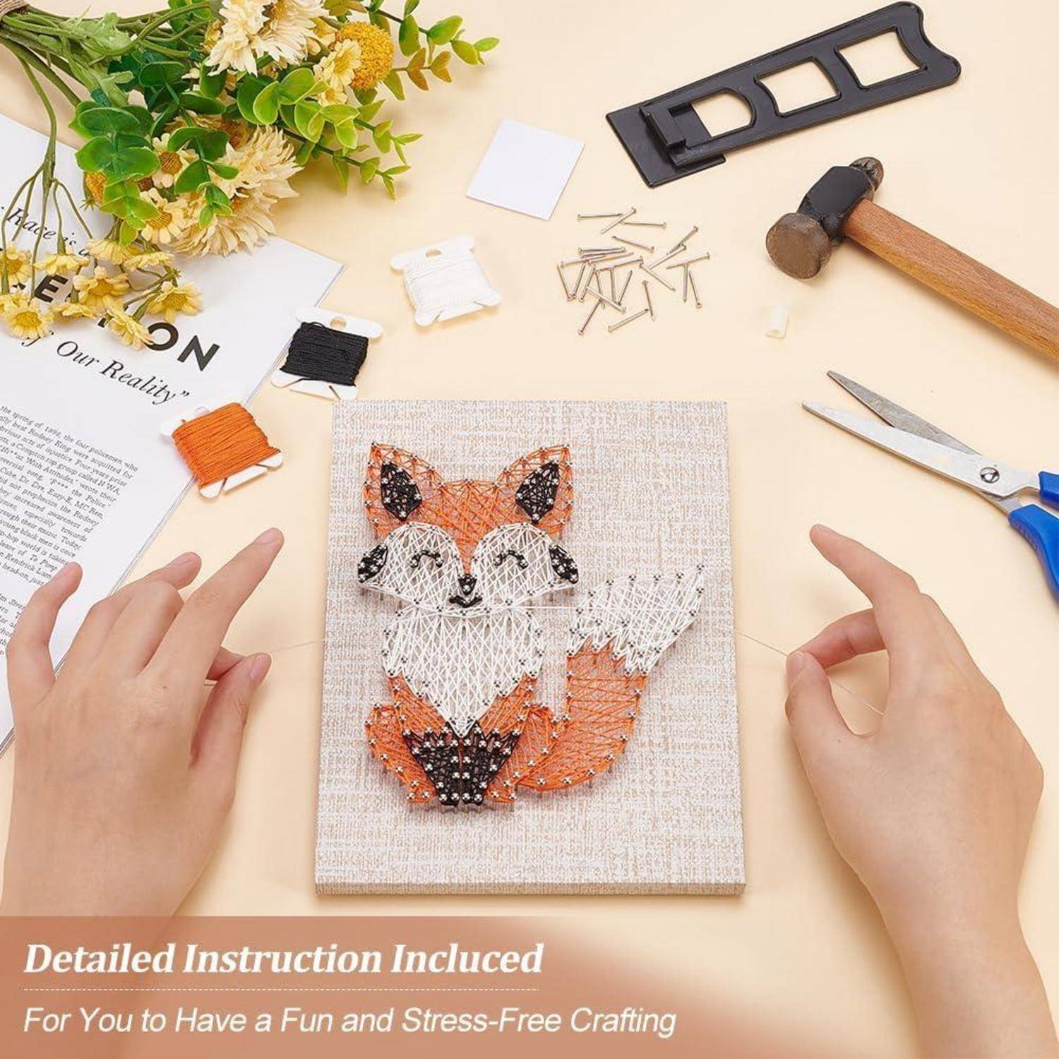 Hände, die ein Fuchs-Fadenkunstwerk auf einer Leinwand anfertigen, mit Garnrollen, Nägeln, Schere und einem Hammer auf einer Werkbank; Text sagt „Ausführliche Anleitung enthalten