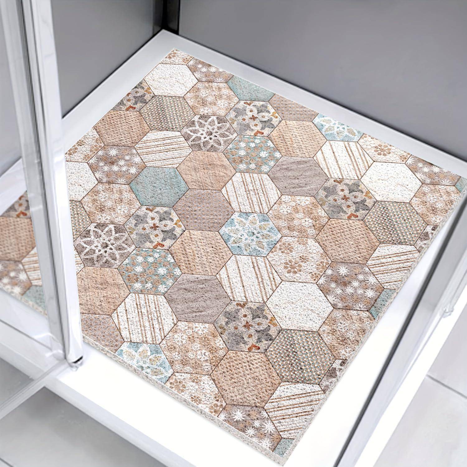 Sechseckig gemustertes Kissen oder Sitzkissen in Beige, Grau und hellem Blau im Patchwork-Stil, platziert auf einem weißen Stuhl oder Hocker.