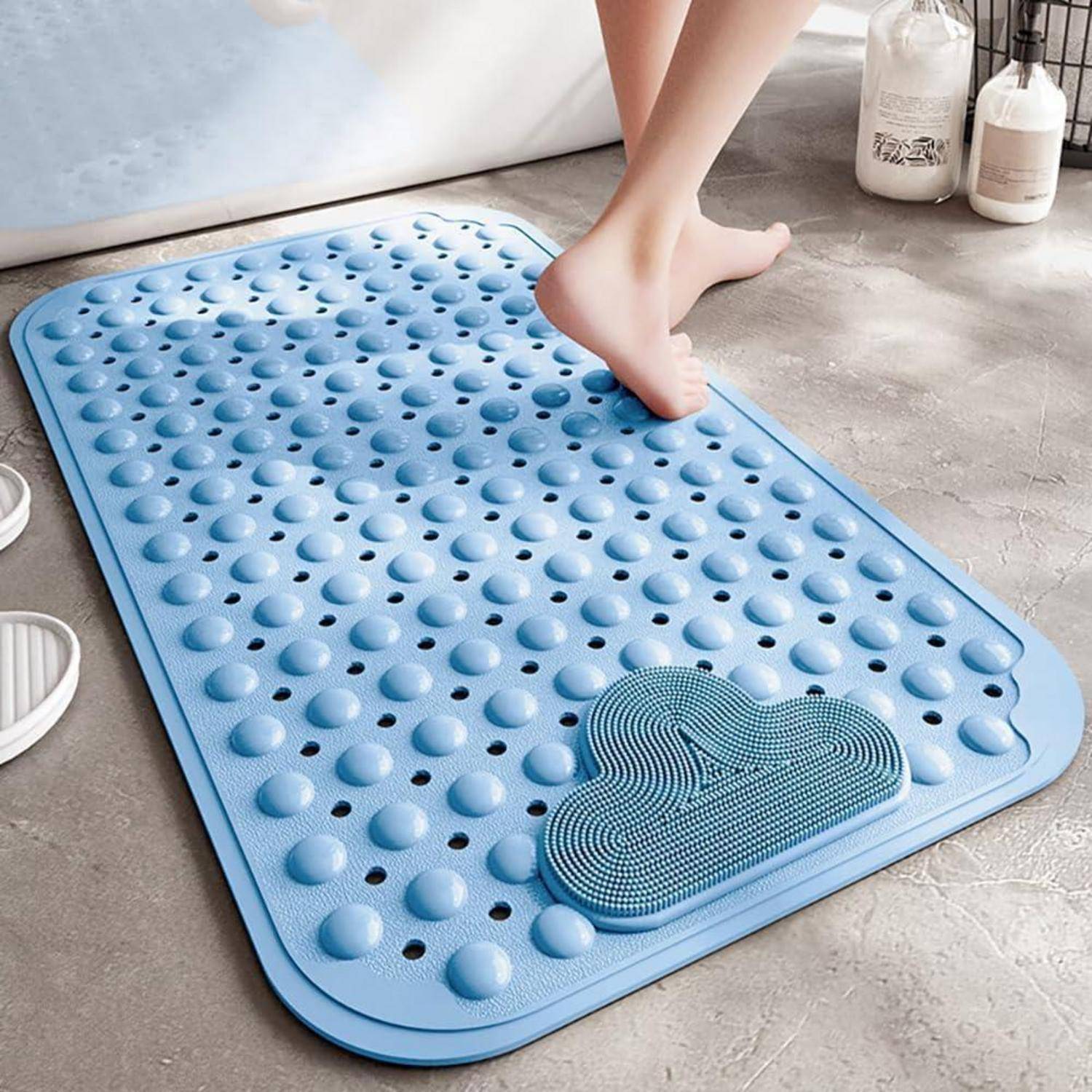Ein Fuß tritt auf eine blau strukturierte Badmatte, auf der sich ein kleiner Reinigungsschwamm in einer Badezimmerumgebung befindet.