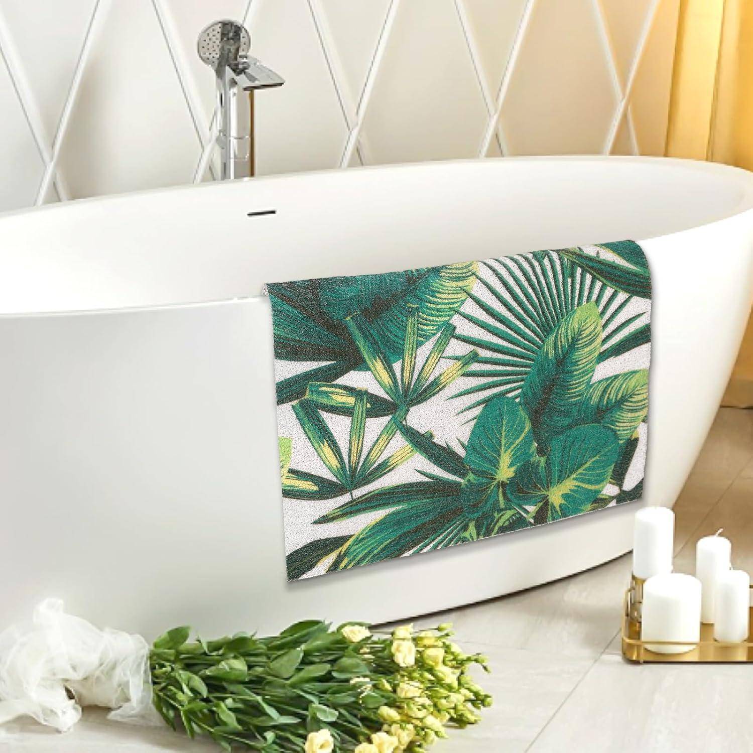Freistehende moderne Badewanne mit tropischem Blattmuster, Blumen und Kerzen in einem hellen Badezimmer.