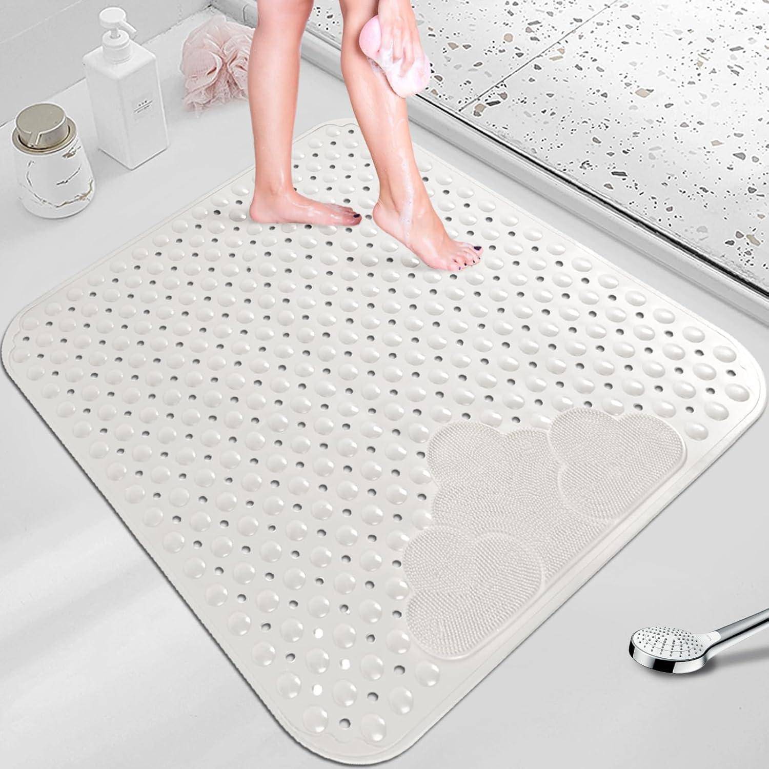 Eine Person, die nackte Füße auf einer weißen strukturierten Badematte im Badezimmer trocknet, mit einer Dusche und Badezimmerzubehör in der Nähe.